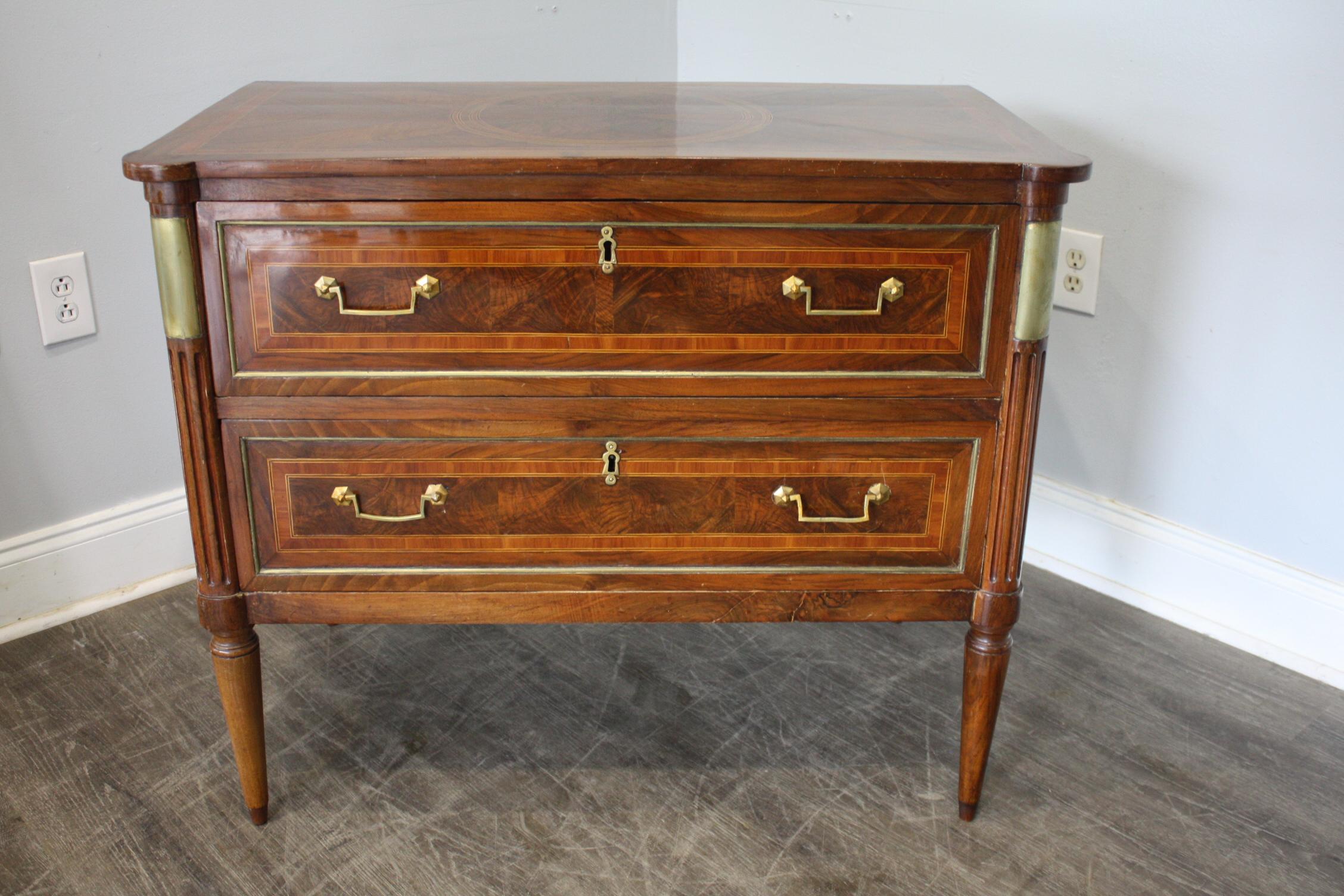 This late 18th century commode is very rich with the different wood, patterns and brass. It is covered with an original veneer.