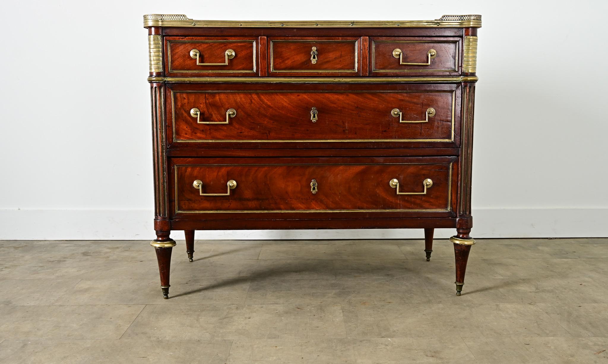 An exceptional Louis XVI period, marble-topped mahogany commode from France that brings regal refinement to any interior. Brass trim with pierced gallery on three sides encloses the (inset) Saint Anne marble top; the stone exhibits a dense