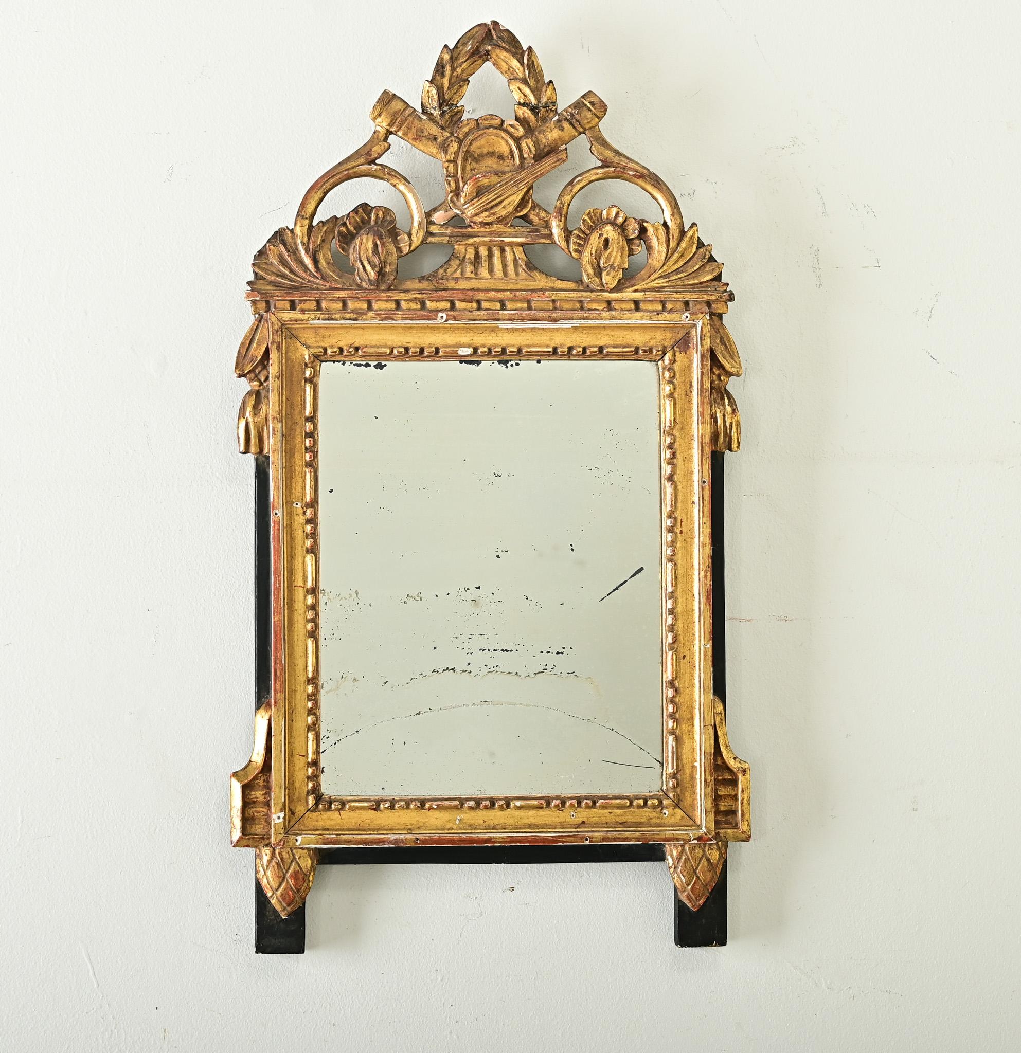 Miroir trumeau raffiné d'époque Louis XVI, datant du XVIIIe siècle en France, avec d'élégantes sculptures en bois doré montées sur un panneau arrière ébonisé. Des sculptures de feuillage en volutes au sommet de la pièce, comme du laurier, attirent