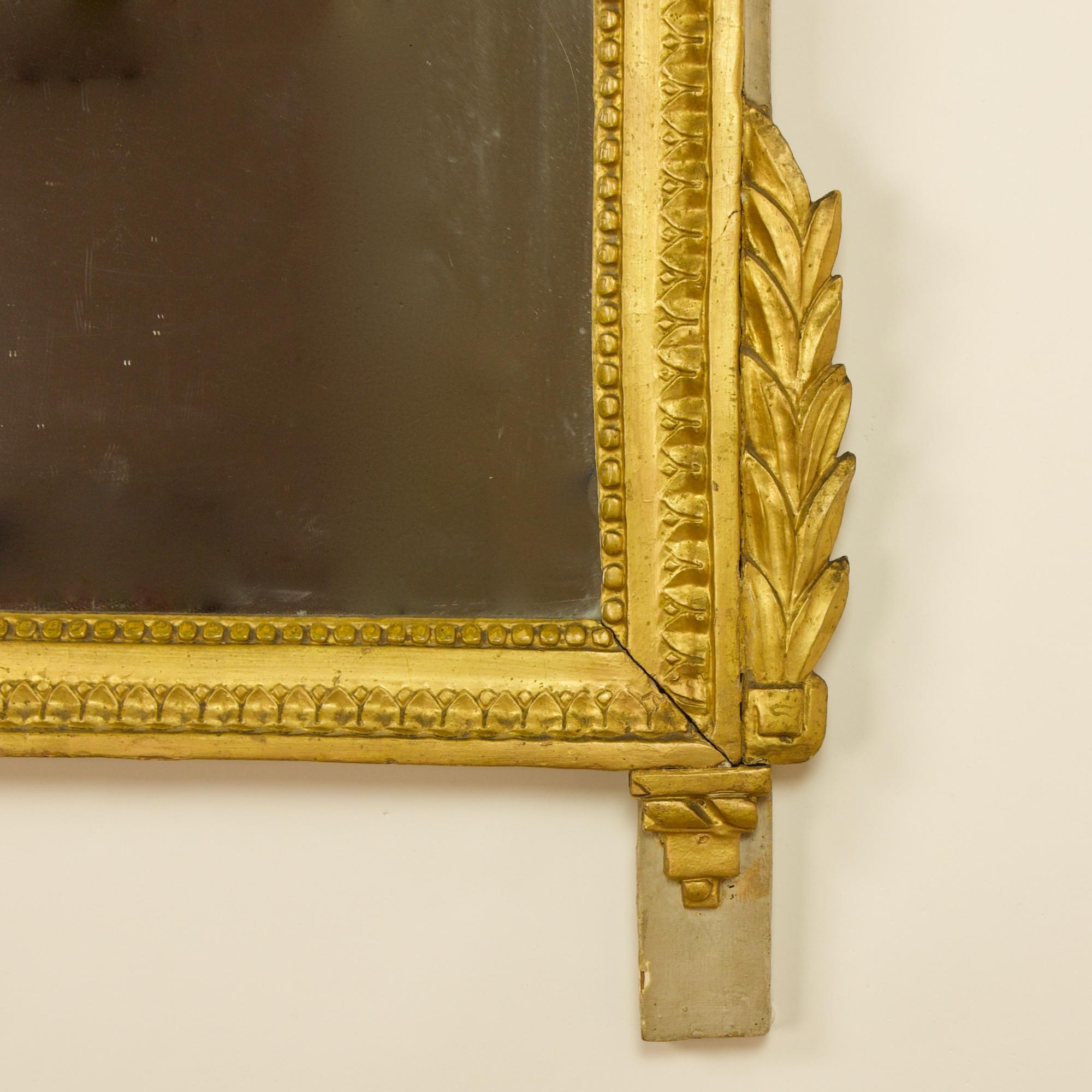 French 18th century Louis XVI giltwood wall mirror or trumeau

The giltwood mirror containing an old mirror plate within a moulded and beaded frame. The cresting showing a neoclassical floral vignette with two large foliage scrolls and leafs with