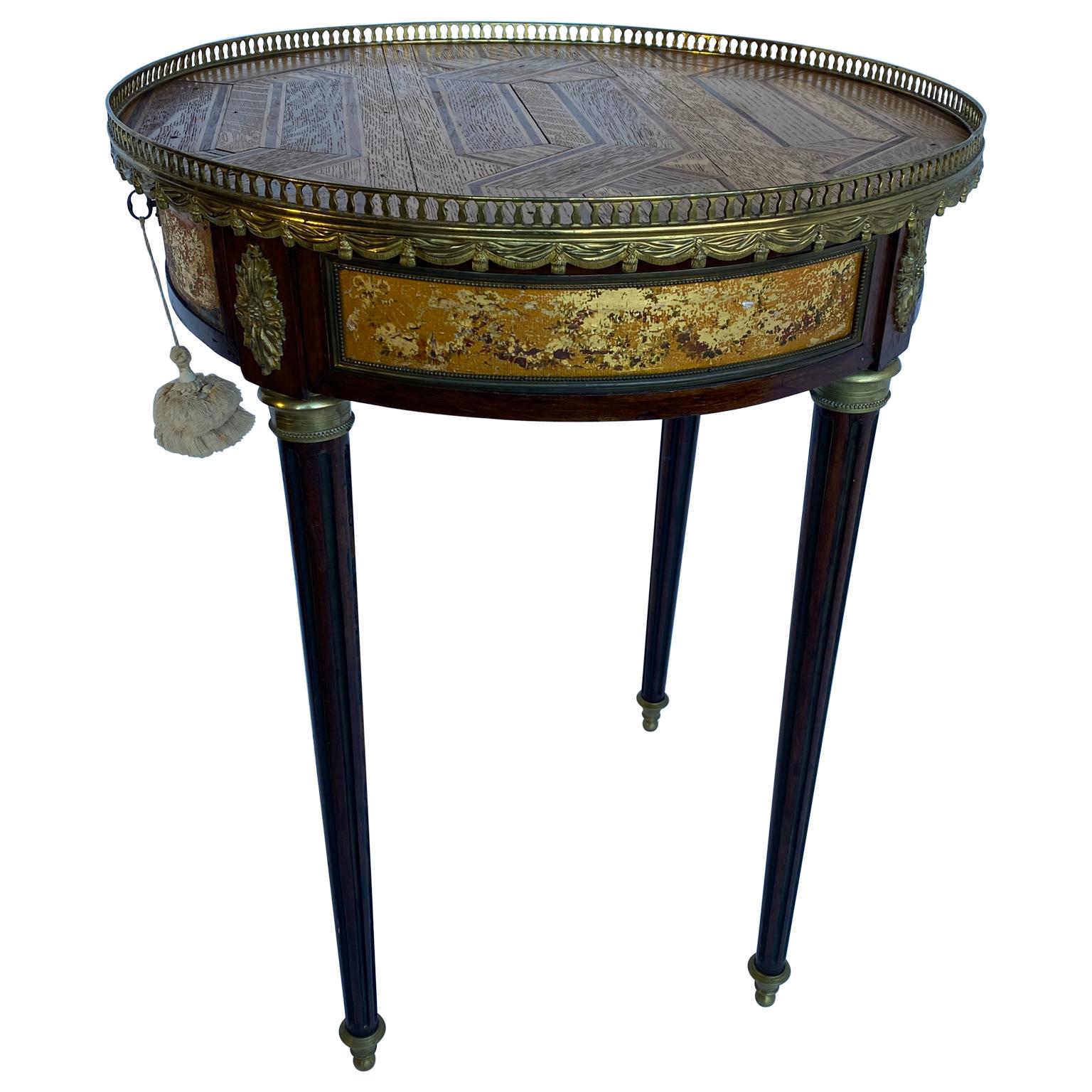 Cette table Bouillotte antique française possède un étonnant plateau de parquet de style Versailles au lieu des habituels plateaux de marbre. Le plateau en parquet est protégé par une période et un tablier orné d'une galerie en laiton doré. La table
