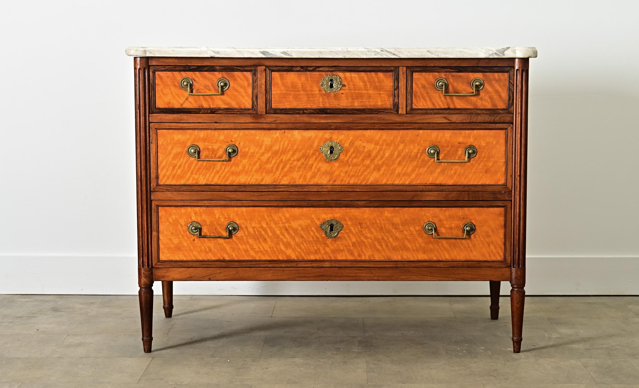 An exceptional Louis XVI period (18th century) marble-topped commode from France, incorporating multiple wood elements with classic details that could suit a wide range of decorating tastes today. The marble top surface exhibits fine veining, a