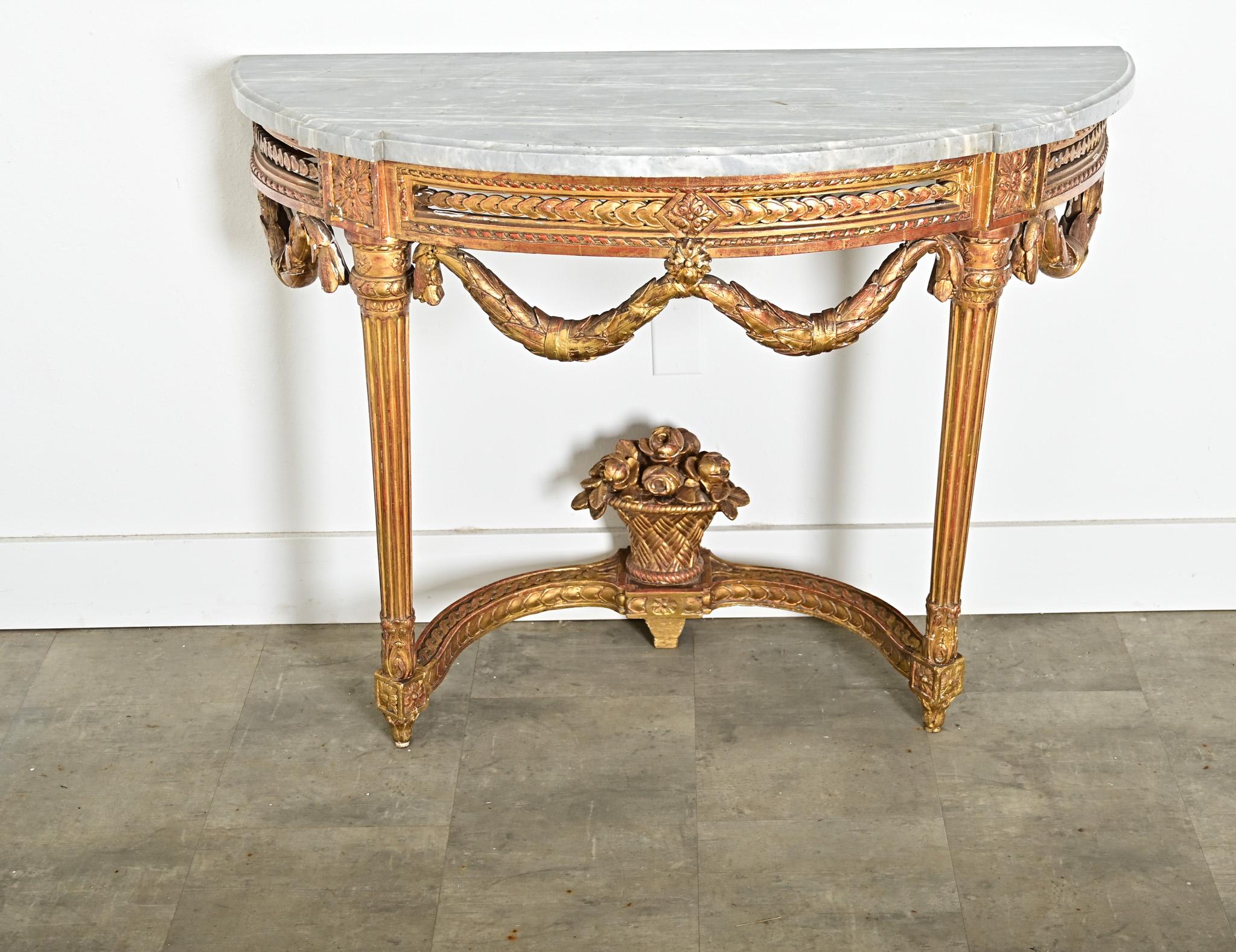 A dramatic French 18th century Louis XVI period demilune-console, with an exquisite giltwood base supporting its original slab of marble. The ethereal gray stone is streaked with white veining, carved by hand to a low, routed edge along the top and