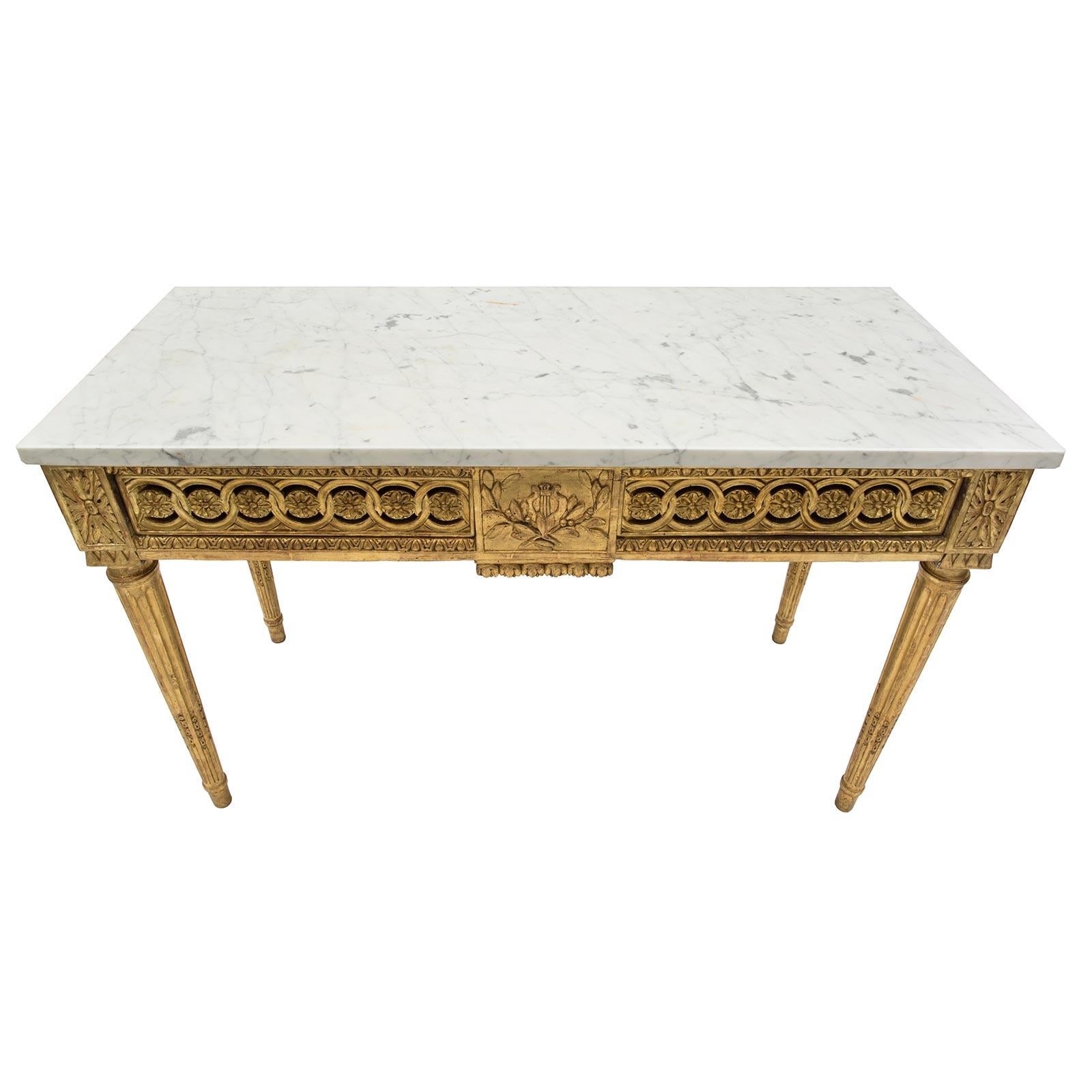 An exceptional French 18th century Louis XVI period giltwood and white Carrara marble center table with two drawers. The table is raised by elegant circular fluted tapered legs with finely carved fitted chandelles. The frieze displays block rosettes