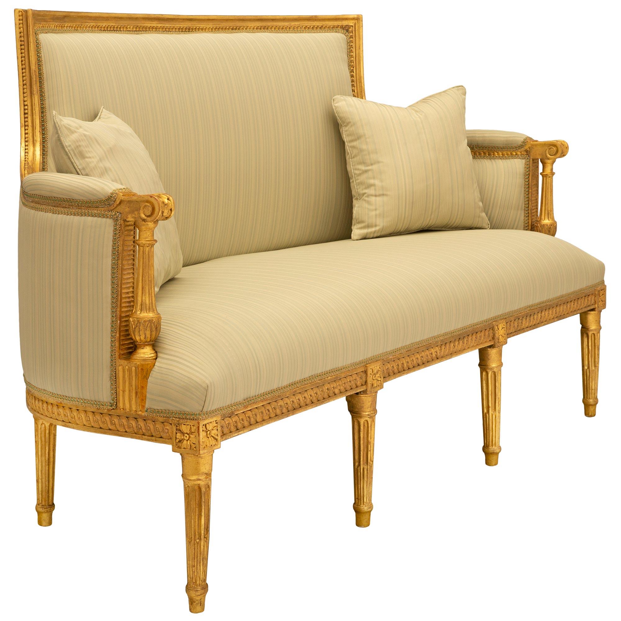 A beautiful and extremely elegant French 18th century Louis XVI period giltwood canapé settee. The settee is raised by seven delicate circular tapered fluted legs below striking block rosettes flanking richly carved recessed interlocking designs