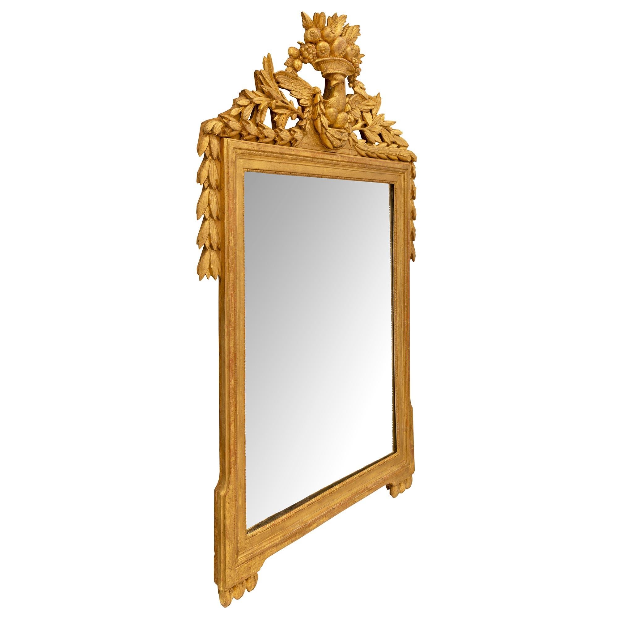 Miroir en bois doré d'époque Louis XVI, du XVIIIe siècle, d'une qualité exceptionnelle. Le miroir a conservé sa plaque d'origine dans un élégant cadre en bois doré tacheté, orné de perles et d'un fin décor gravé à l'eau-forte. La majestueuse