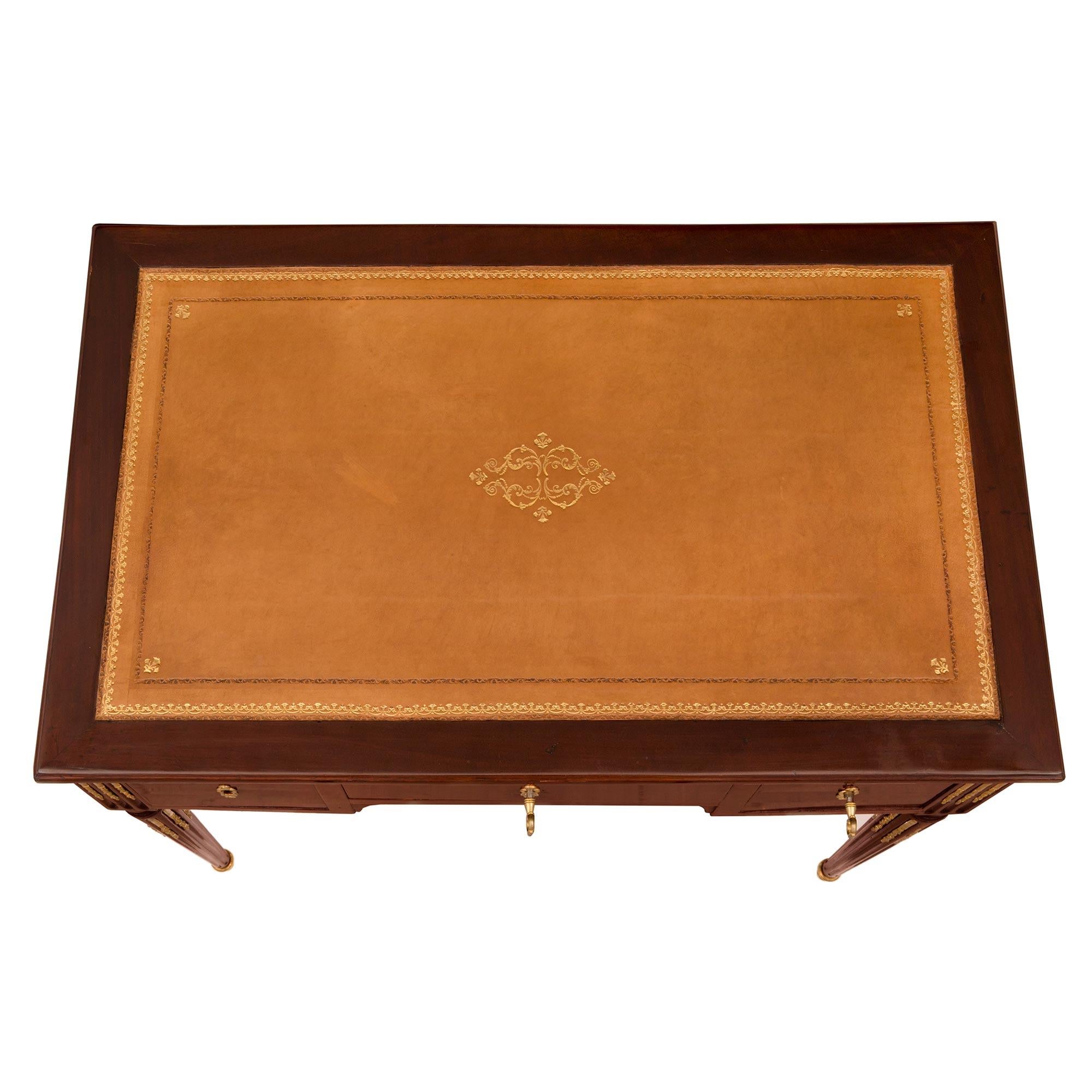 Bureau ou table à écrire de très haute qualité, d'époque Louis XVI, en acajou et bronze doré, signé C. Mauter. Le bureau est surélevé par d'élégants pieds circulaires fuselés et cannelés, dotés de sabots en bronze doré et de chandelles feuillagées