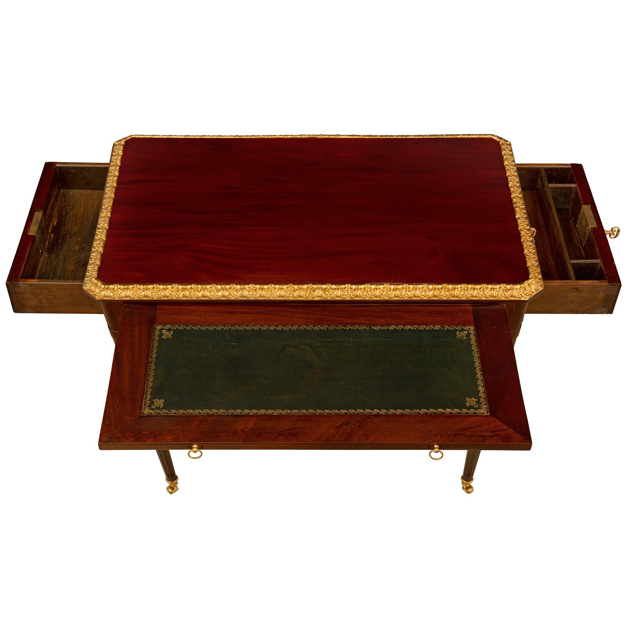 An elegant and very high quality French 18th century Louis XVI period Mahogany and ormolu side table/desk. The two drawer rectangular table with a pull out is raised by slender circular tapered fluted legs with their original ormolu casters. The