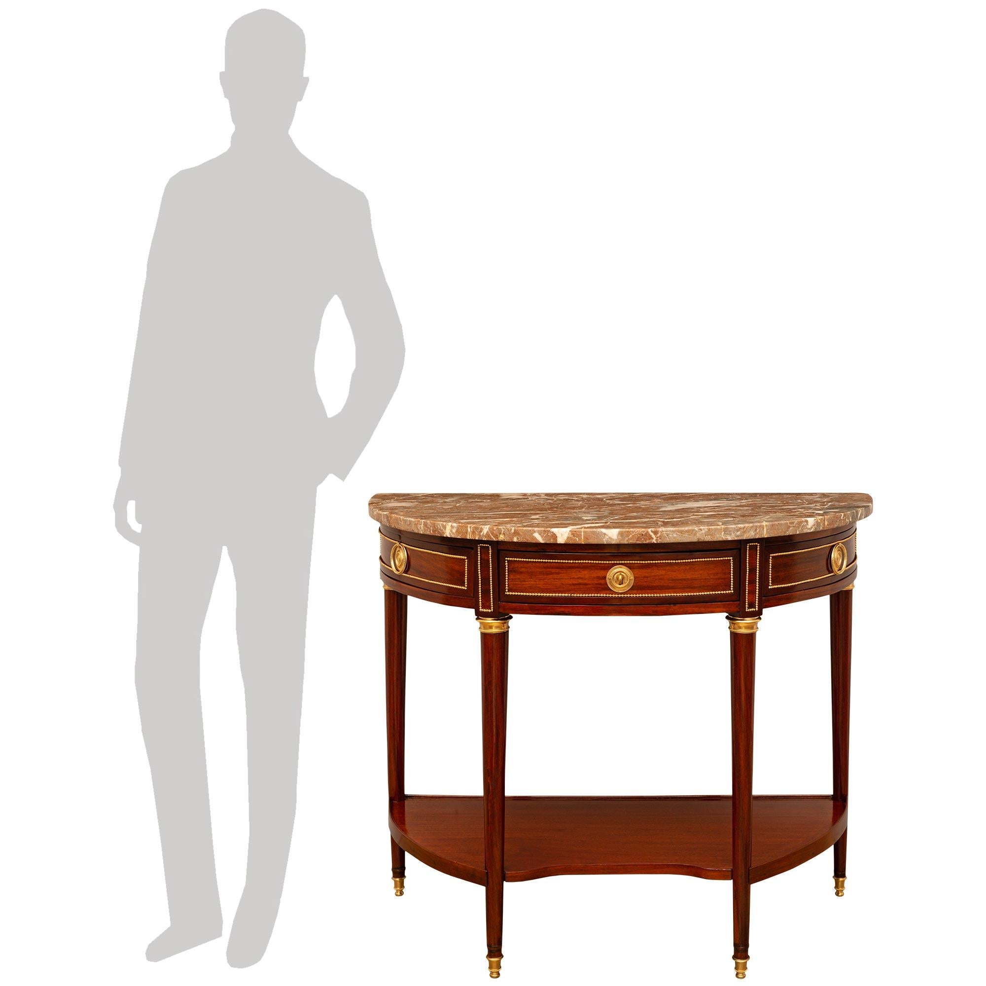 A stunning and high quality French 18th century Louis XVI period Ormolu, Mahogany, and Rouge Royale marble console. This beautiful three drawer console is raised by four circular tapered legs with Ormolu topie shaped feet and mottled Ormolu top