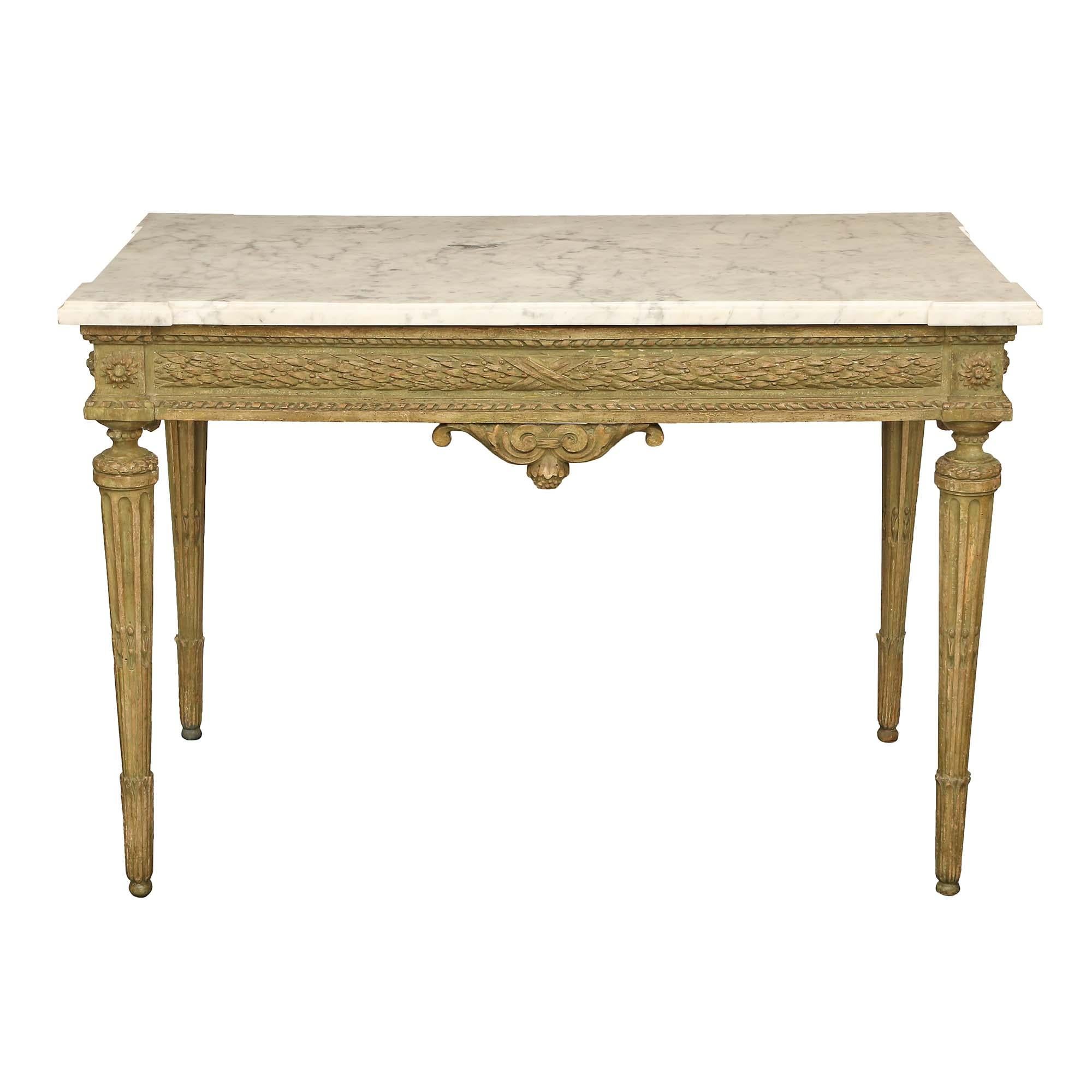 A lovely French 18th century Louis XVI period patinated center table with the original marble top. The table is raised by circular tapered fluted legs with foliate accents. The straight frieze is centered by a scrolled reserved and acorn finial