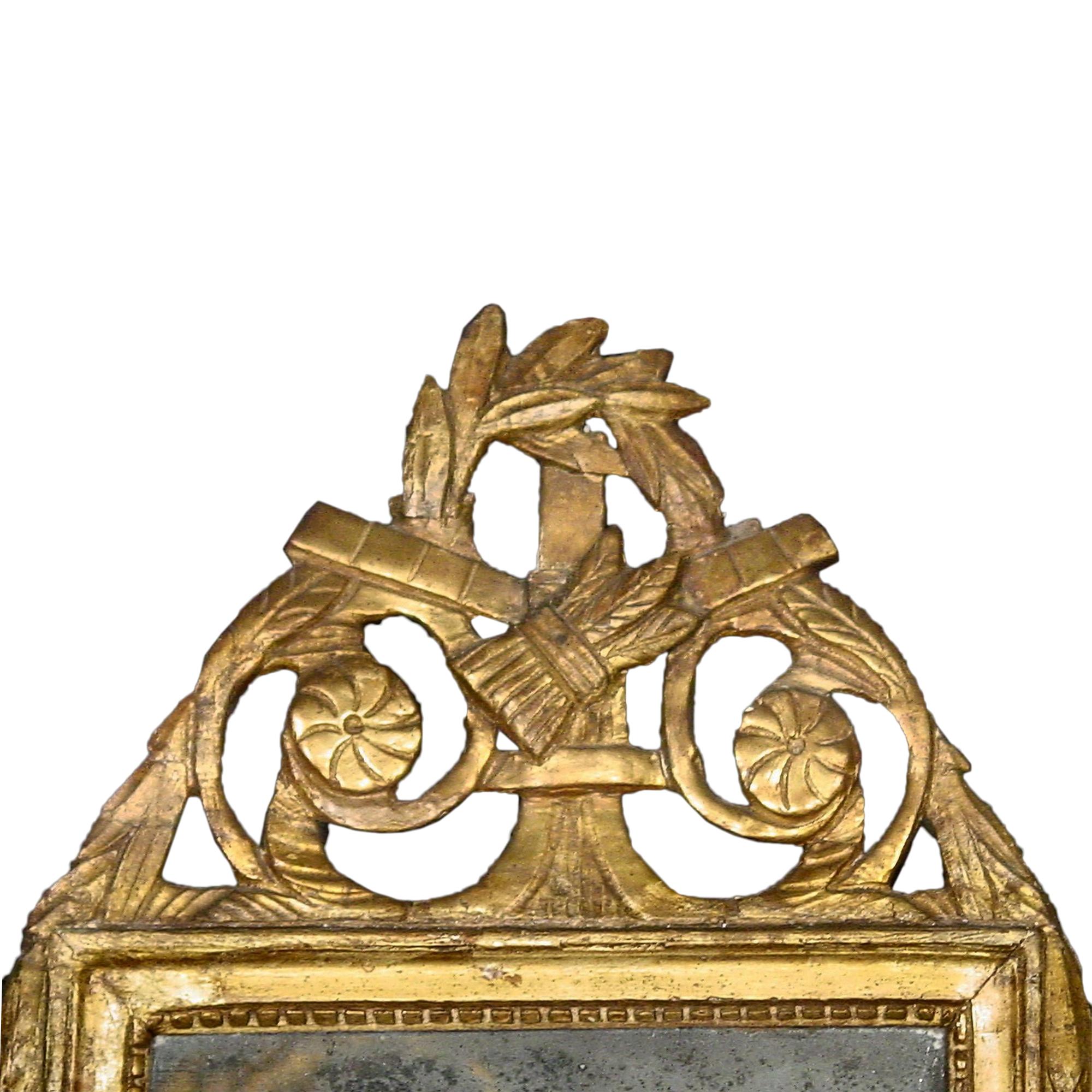 A charming country French 18th century Louis XVI period patinated green and gilt mirror. The top has wonderful gilt carvings of wheat amidst wreaths of foliage and farming tools. Elegant scrolls with rosettes finish the top central reserve. The