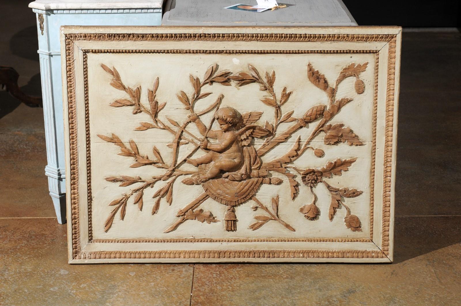 A French Louis XVI period low-relief carved and painted wooden panel from the late 18th century, with cherub and foliage. Born in France during the later years of the 18th century, this exquisite wooden wall panel attracts our eye with its skilfully