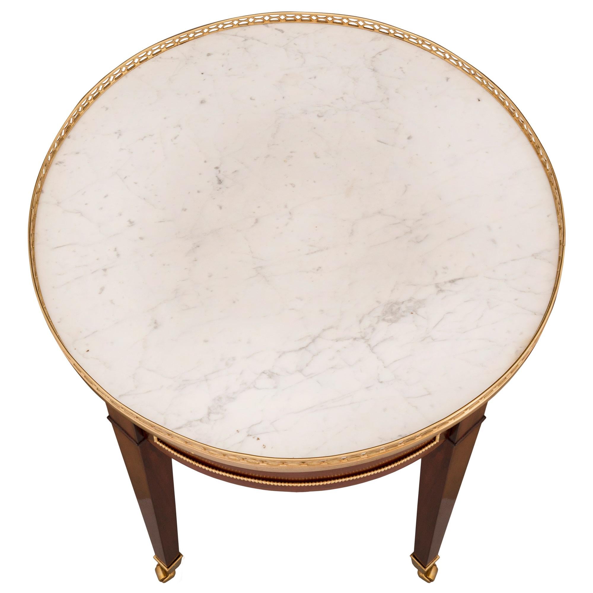 A superb French 18th century Louis XVI st. mahogany, ormolu and white Carrara marble side table. The table is raised by elegant square tapered legs with their original unique and most decorative casters. The apron displays four recessed panels with