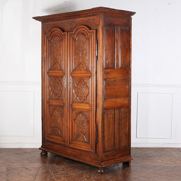 Magnificent French 18th century Lyonnaise carved walnut armoire with a bold dentil- molded crown above a pair of highly-carved arched top doors featuring carved flora and birds. Paneled sides. Wonderful old surface with deep warm patina. C.
