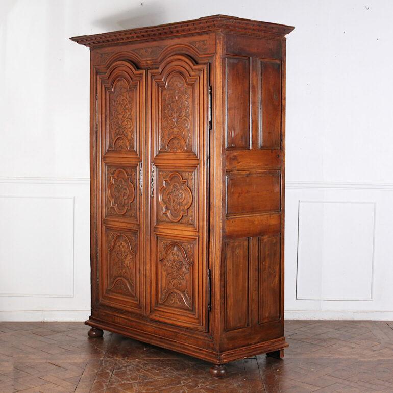 Magnifique armoire française du XVIIIe siècle en noyer sculpté à la Lyonnaise, avec une couronne audacieuse moulée en denticules au-dessus d'une paire de portes supérieures arquées très sculptées, avec des plantes et des oiseaux sculptés. Côtés