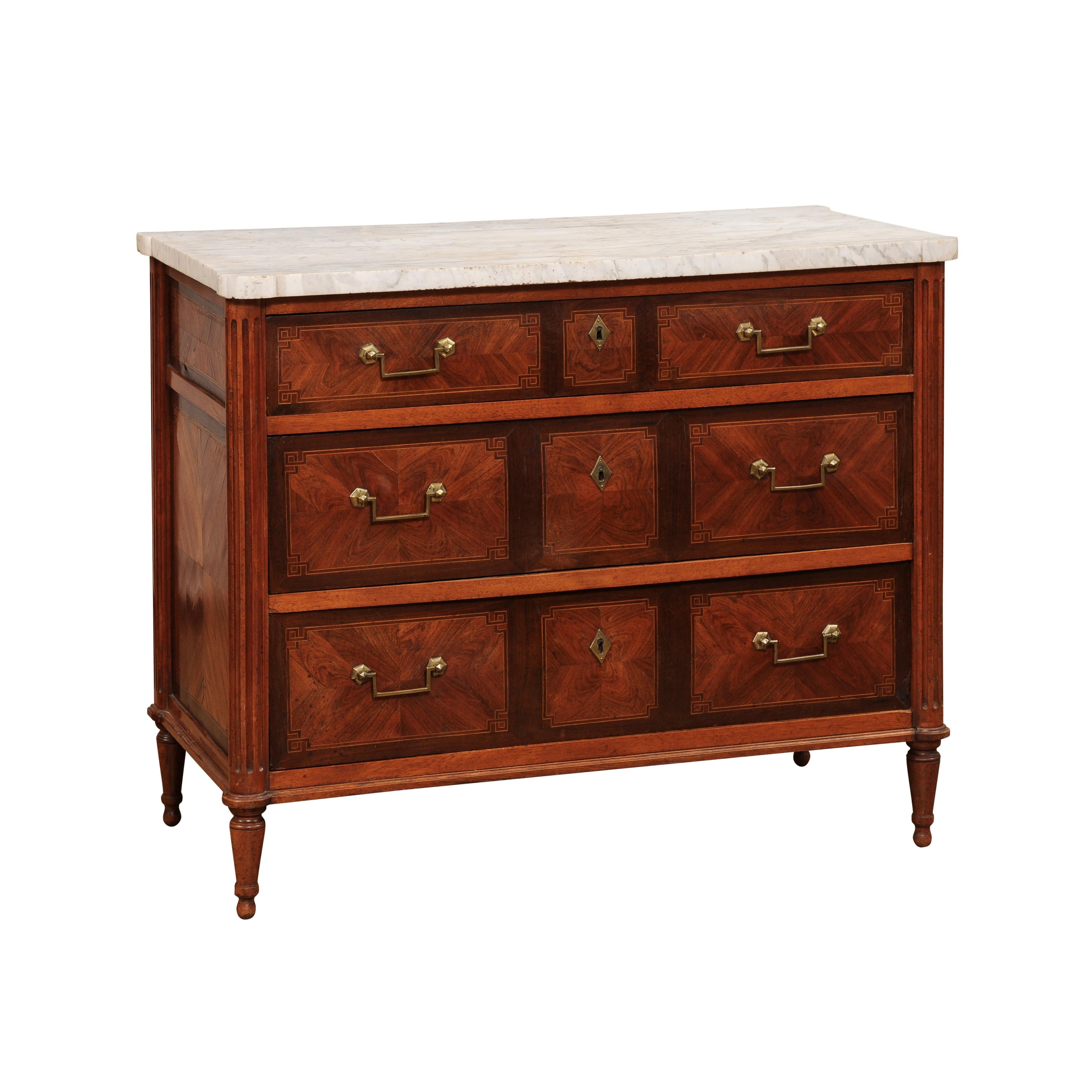 A French mahogany and rosewood commode from the 18th century with white marble top, fine details and bookmatched veneer. Add elegance and sophistication to your home with this stunning French mahogany and rosewood commode from the 18th century.