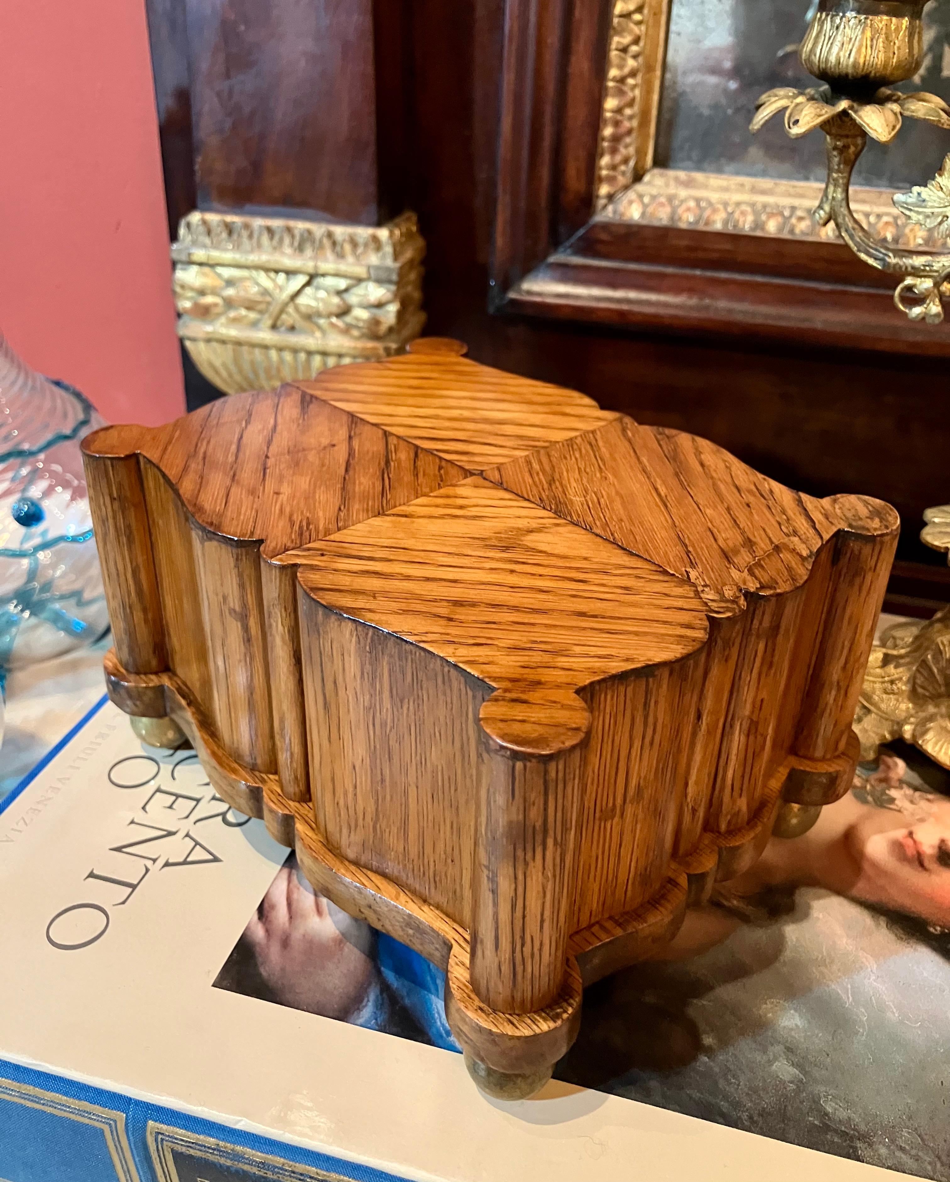 This exquisite French 18th-century oak collectible box is a testament to masterful craftsmanship. Its charming, rounded form is enhanced by meticulously executed herringbone marquetry, showcasing the rich grain of the oak.  Resting on four gilded