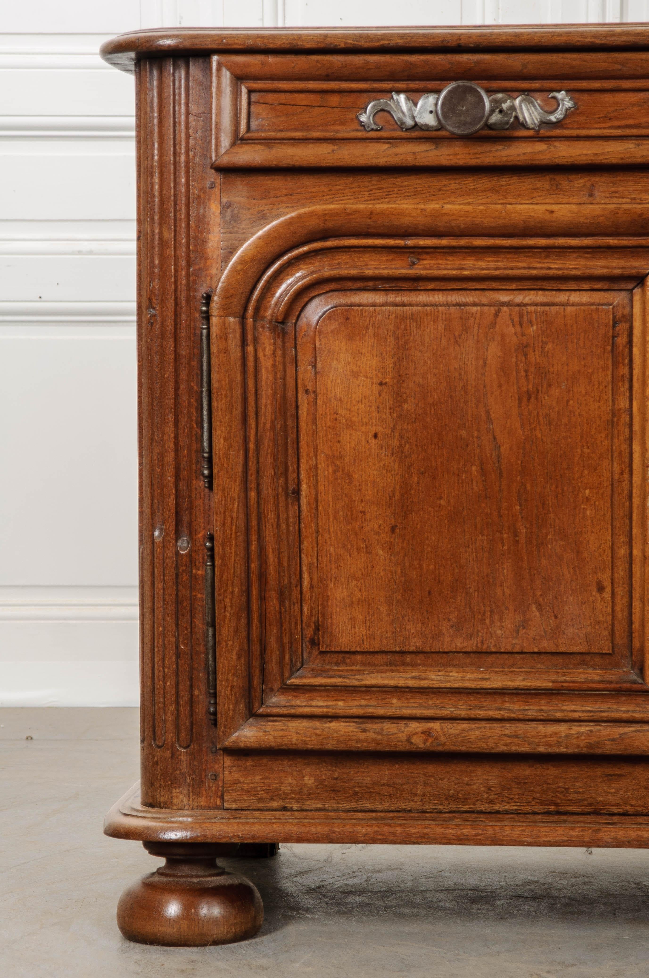 A hefty oak buffet, made in France towards the middle of the 18th century. The buffet has been constructed using thick, sold pieces of milled oak that contribute to the antique’s heft. Rounded corners can be found on the case piece’s fronts and top.