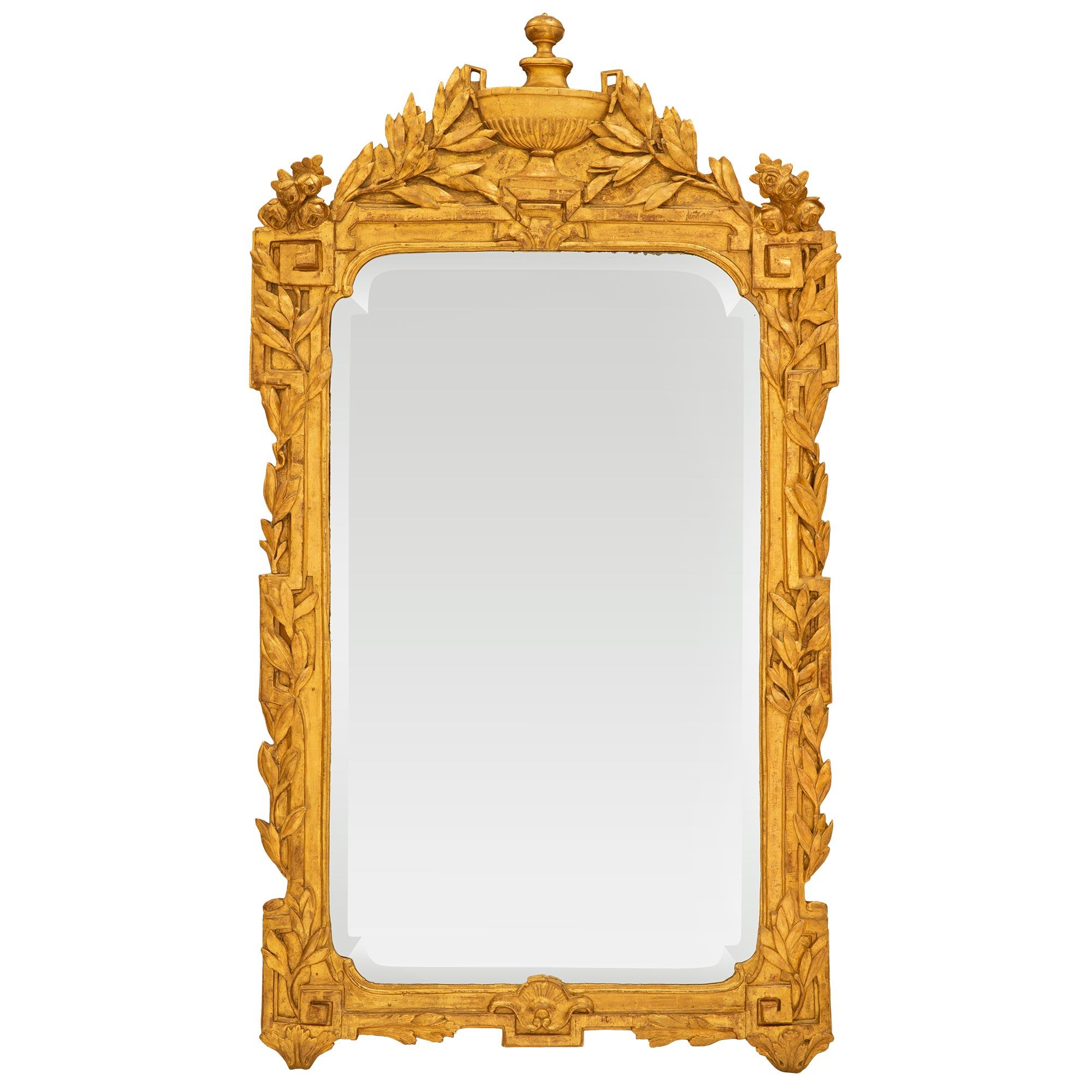 Superbe miroir en bois doré de la période Régence du XVIIIe siècle. Le miroir est doté de la plaque biseautée d'origine dans un cadre en bois doré. Le cadre présente un motif de clé grecque orné de guirlandes feuillagées finement sculptées de chaque