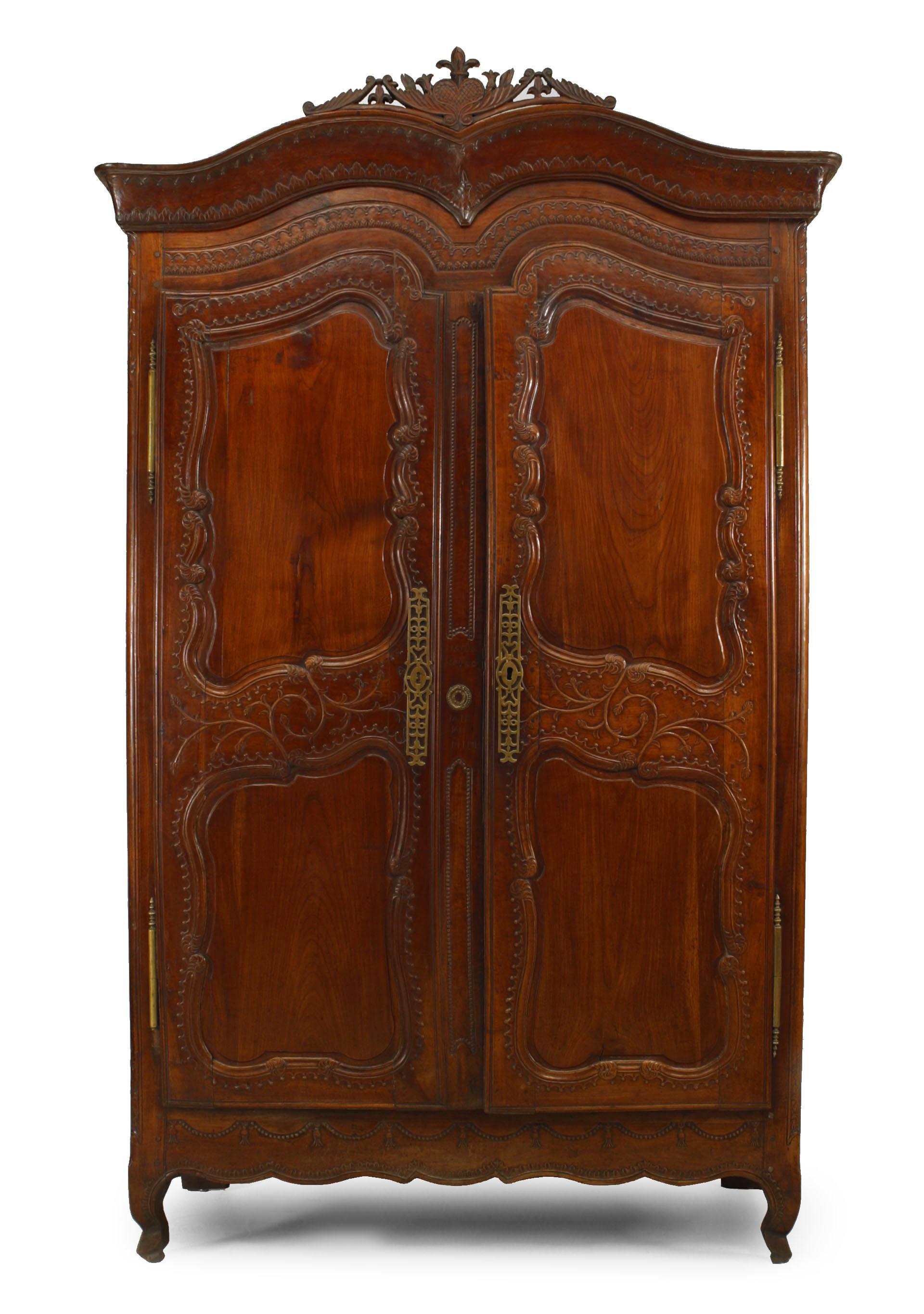 French Provincial 18th century walnut carved armoire with double scroll top and 2 doors with carved border.
