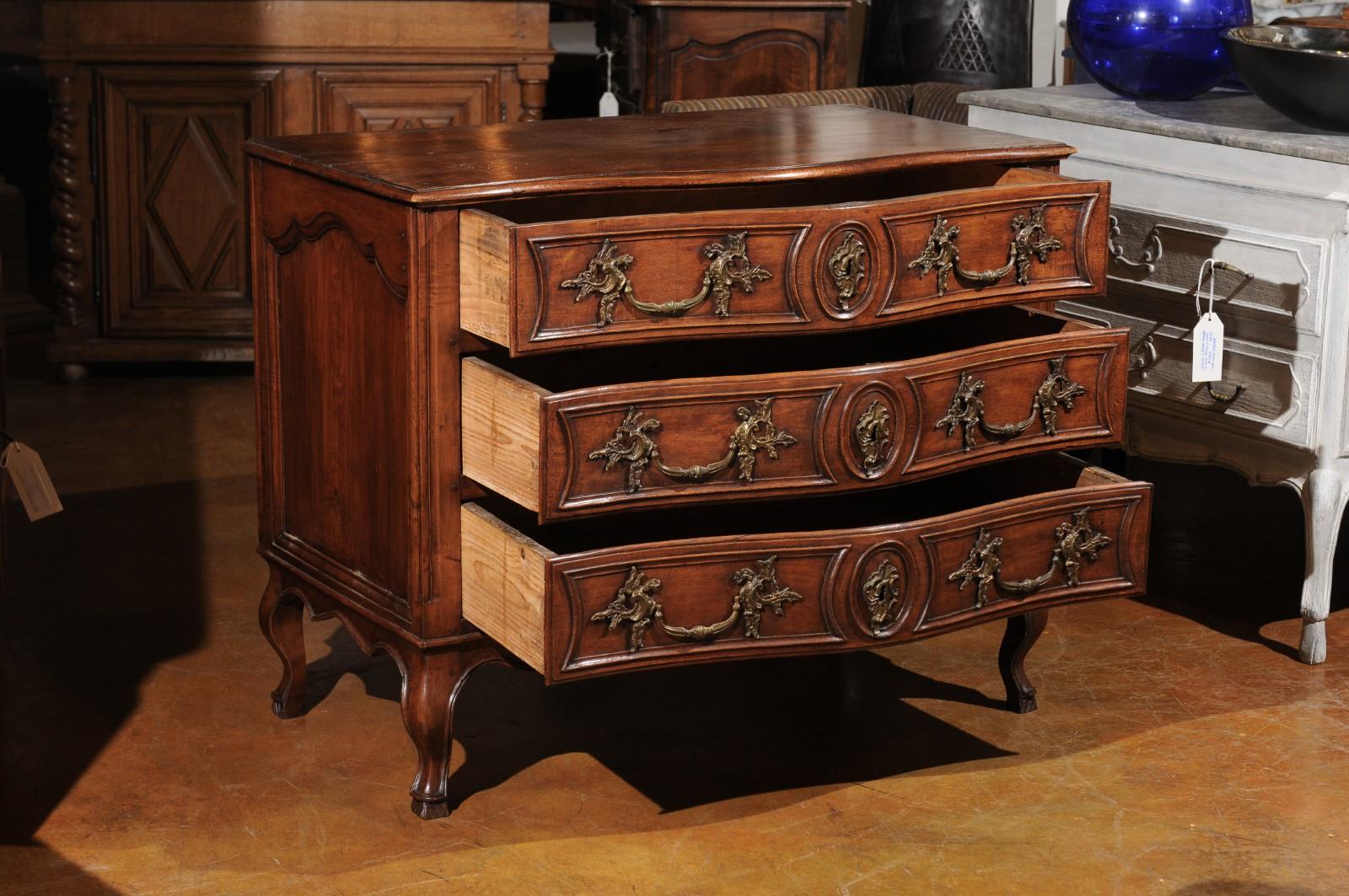 A French Régence beechwood serpentine front commode from the early 18th century, with three drawers and cabriole legs. Born in France after the death of the Sun King, this beechwood commode features a rectangular top with serpentine front, sitting