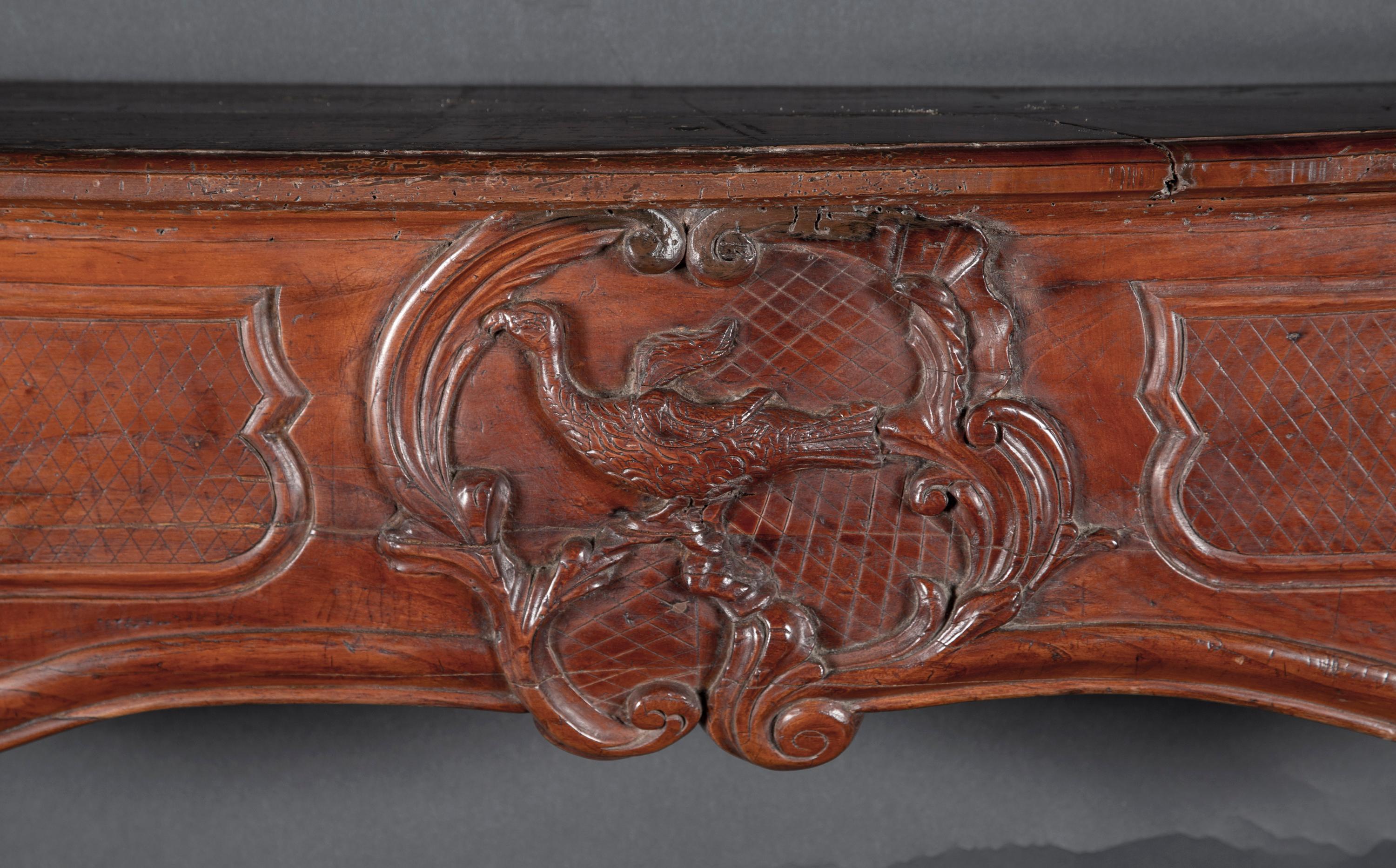This classic Regence mantel of cherrywood is beautifully carved in the floriate manner. The French antique piece dates back to the 18th century and offers classic countryside details.  At center, we see a dove with a cross hatched background