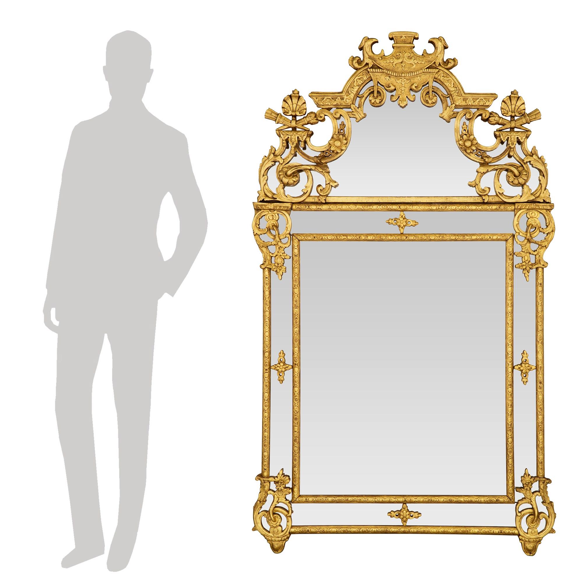 A stunning French 18th century Regence period double framed giltwood mirror. The central original mirror plate is framed within a finely carved giltwood band with an interlocking design. The original outer mirror plates are also framed within the