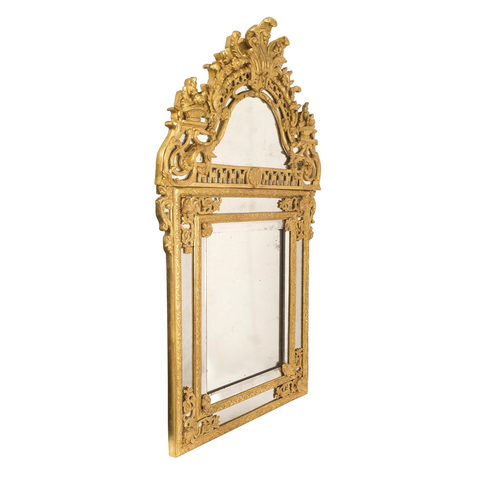 Superbe miroir en bois doré à double cadre de la période Régence du 18e siècle. Le cadre présente des motifs feuillagés saisissants et très détaillés, ainsi que de belles réserves d'angle détaillées et percées de feuillages. La majestueuse couronne