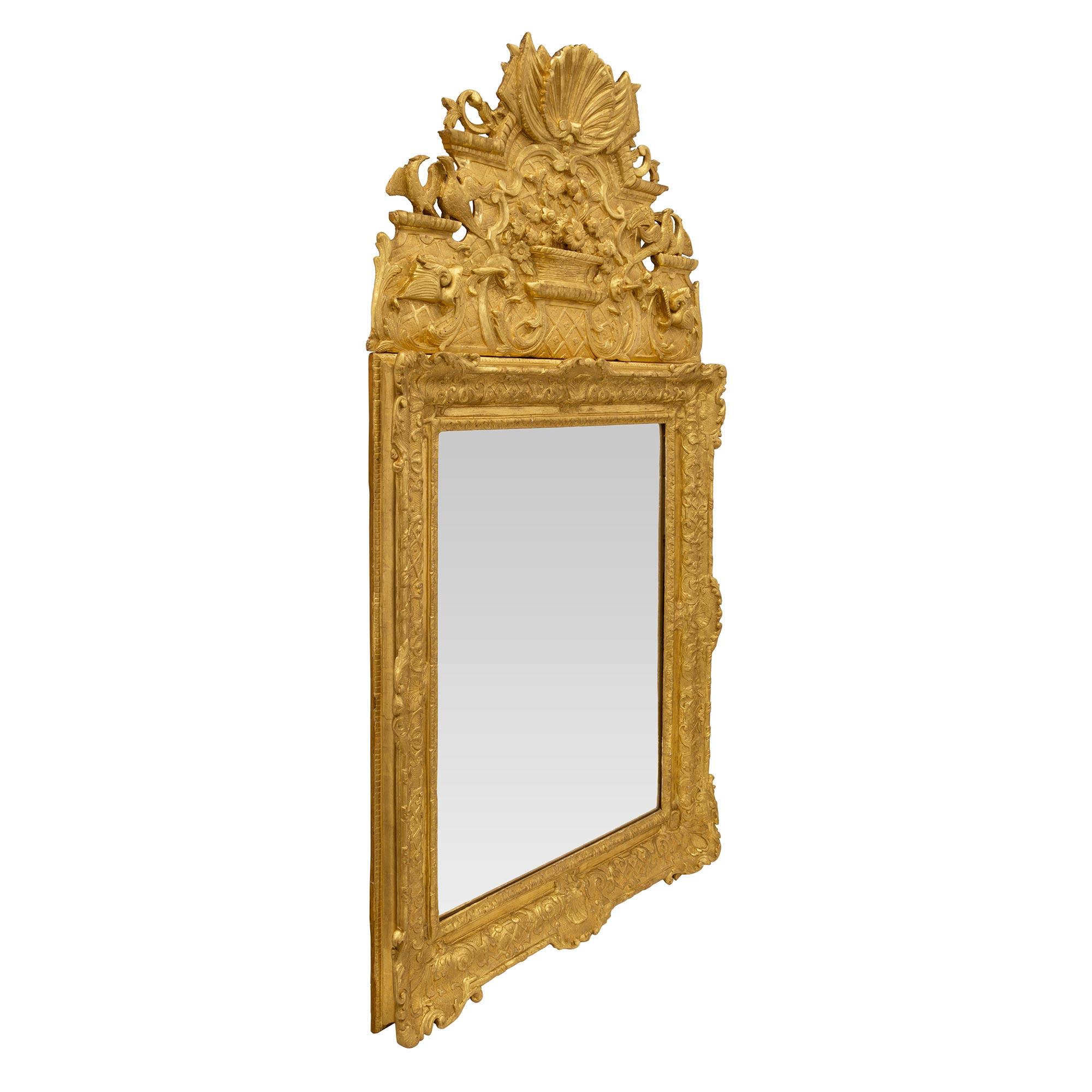 Exceptionnel miroir en bois doré d'époque Régence du XVIIIe siècle. La plaque de miroir d'origine est encadrée d'une fine bordure de feuillage moucheté. Des réserves de coquillages richement sculptés et des motifs imbriqués très décoratifs
