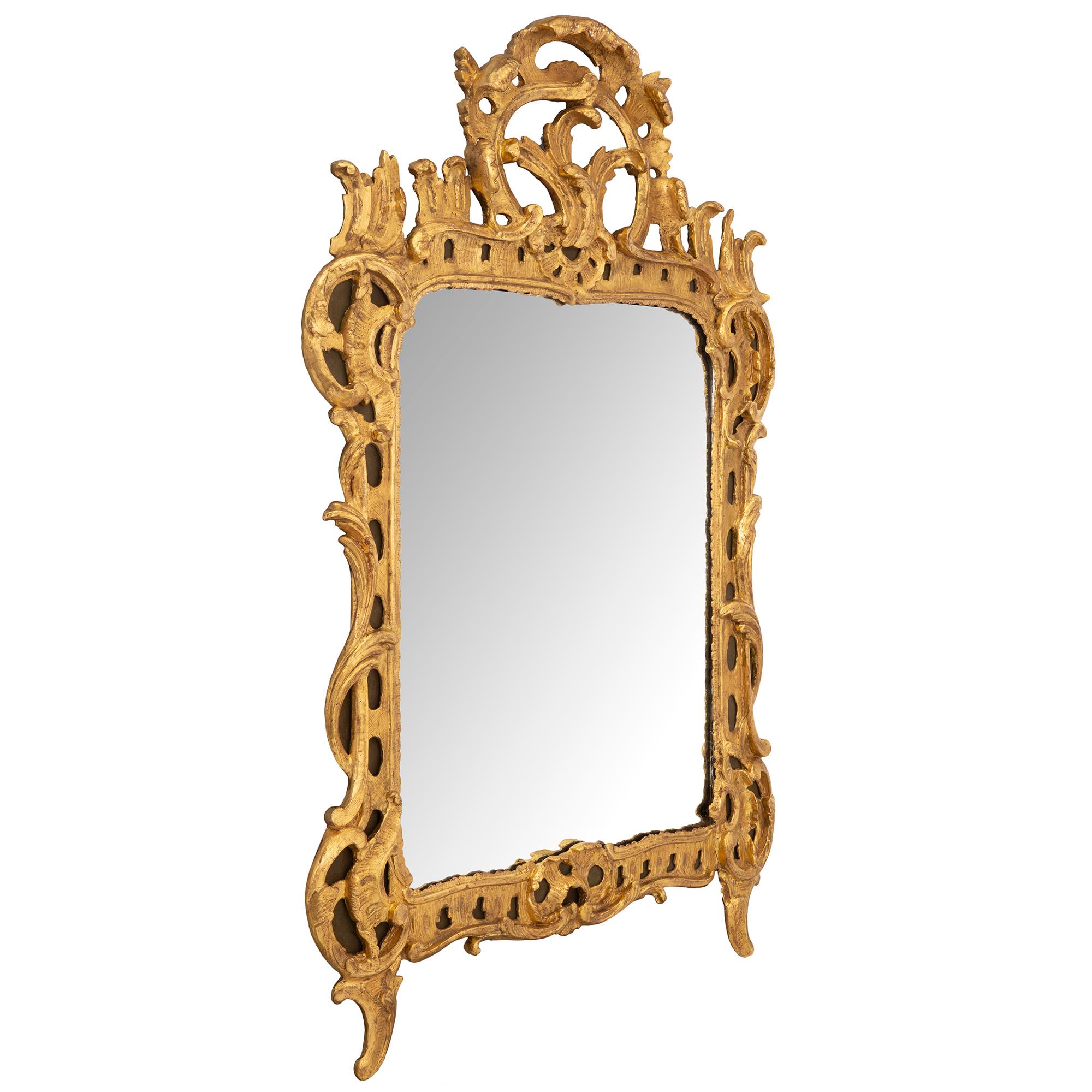 Un'elegante specchiera francese del XVIII secolo in legno dorato del periodo Régence. La lastra originale dello specchio è incorniciata da un bordo in legno dorato con graziosi movimenti foliati smerlati e suggestivi disegni traforati. Belle foglie