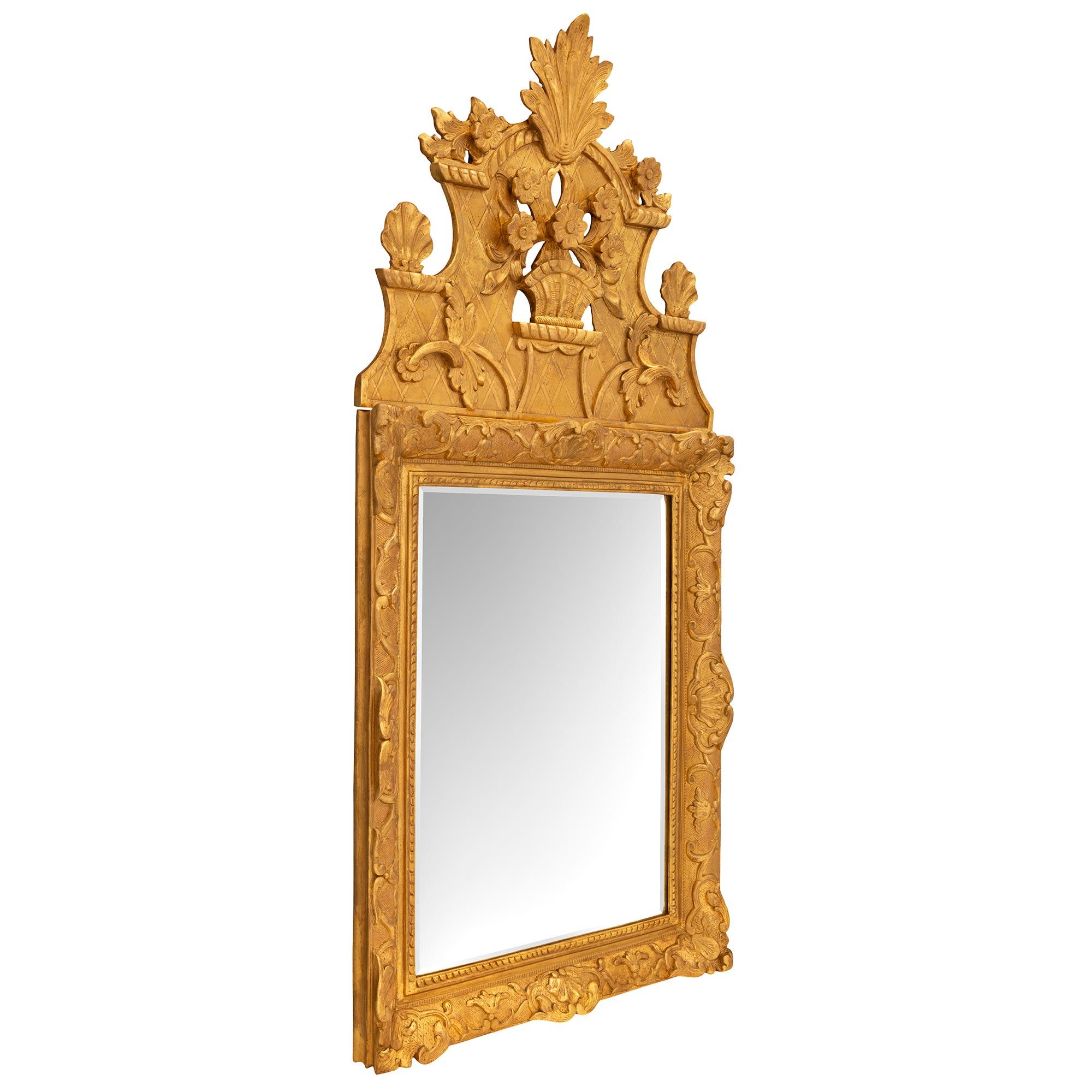 A beautiful French 18th century Regence period giltwood mirror. The mirror retains its original beveled mirror plate set within an elegant mottled and twisted ribbon border. The frame displays superb richly carved scrolled foliate designs set on an