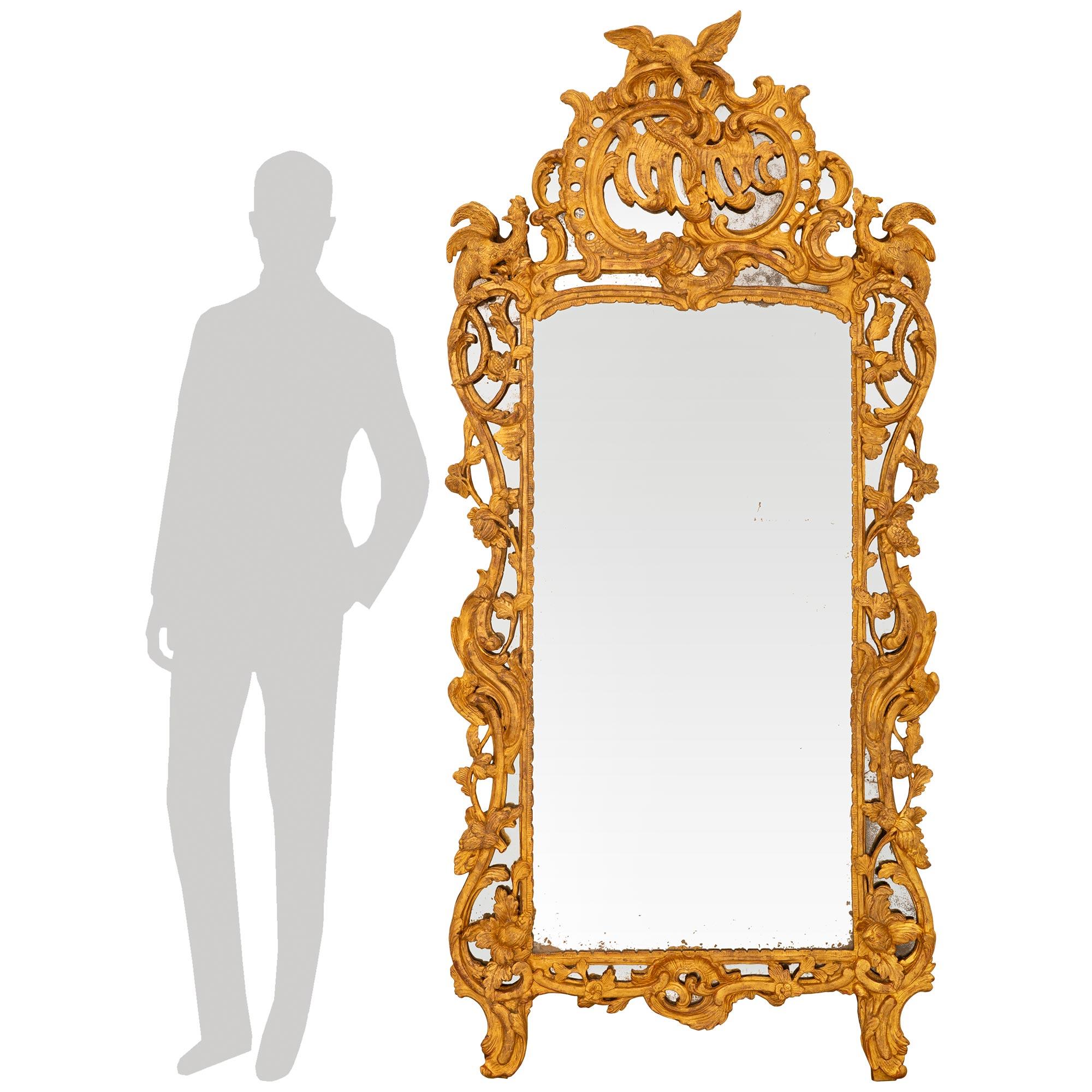 Un miroir en bois doré d'époque Régence du XVIIIe siècle, attrayant et très élégant. Ce superbe miroir à double cadre de grande taille repose sur deux pieds sculptés de rinceaux et est placé dans un cadre intérieur rectangulaire présentant des