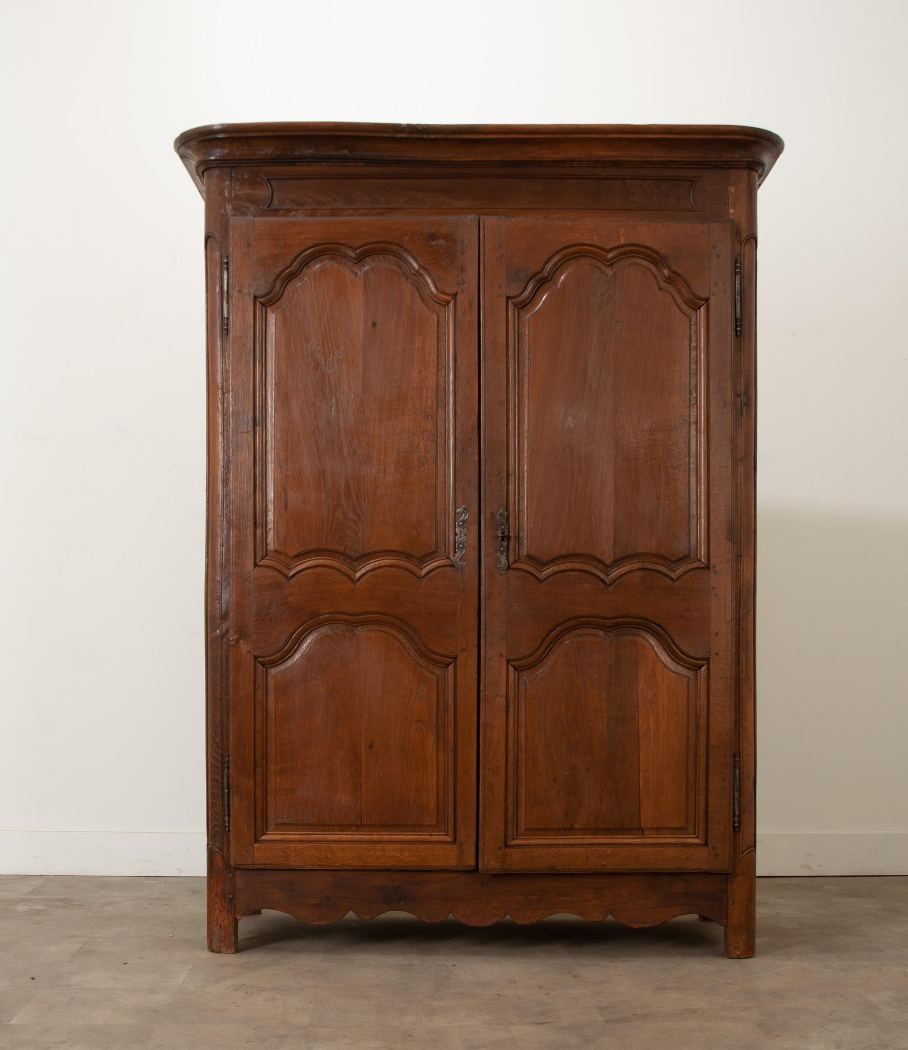This French 18th century armoire in the Louis XV style has a fantastic dark oak finish and gorgeous hand carved details. This piece retains its original locking systems and one key. The pair of doors unlock to reveal a large storage cavity with