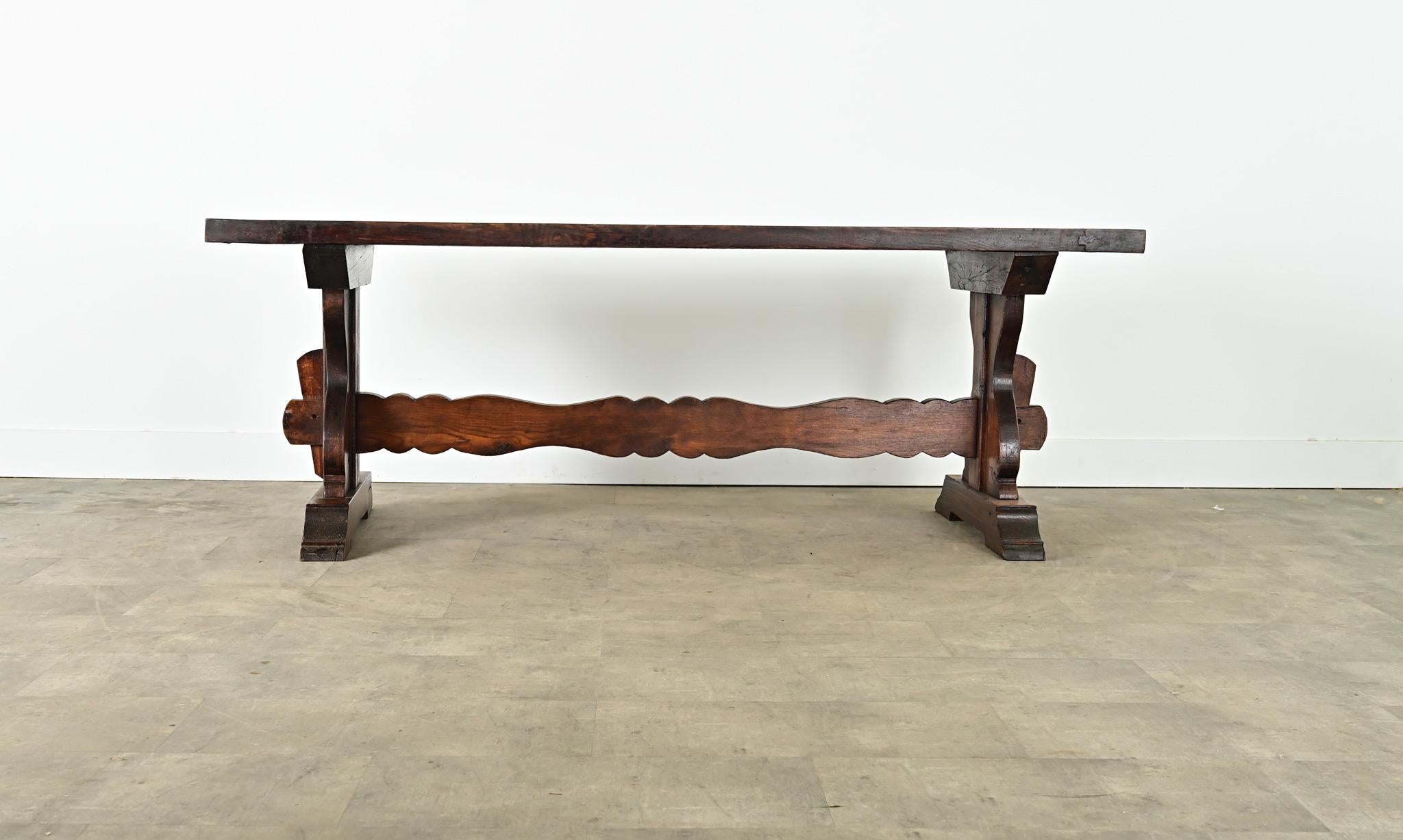 A massive 18th century French oak trestle table with whimsical carved details in the base. Impossibly heavy top planks, arranged in a breadboard formation, create a solid surface for dining or working if using this table as a desk. Typical of