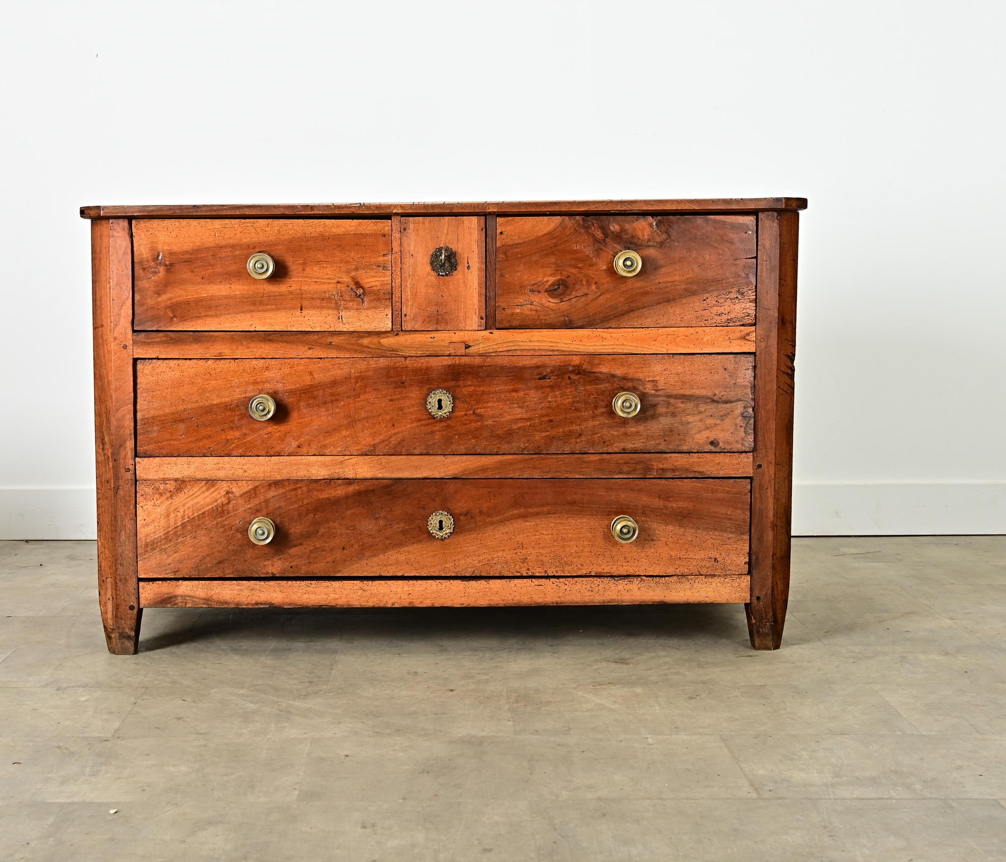 This French, 18th century solid carved walnut commode exhibits strong proportions and generous storage capacity within a case of five drawers below an angular plank top, notched at the front corners and dotted with visible square peg joinery among