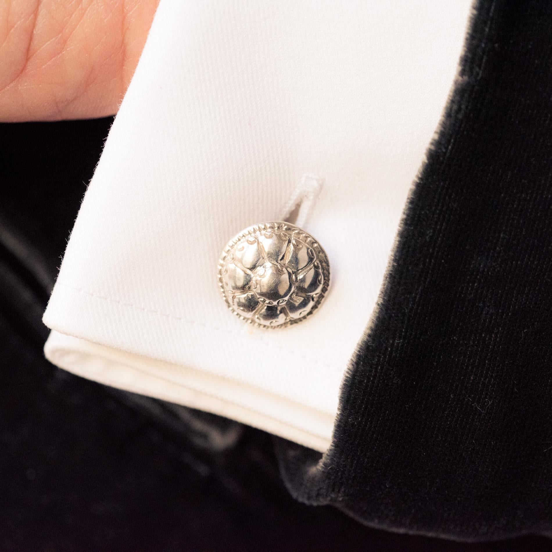 Pair of cufflinks in silver.
Rounded in shape, they are decorated in relief with a flower bordered by a carving. One is held to the other by an oblong ring.
Diameter: 15.5 mm, thickness: approximately 4 mm, Length of central ring: approximately 18