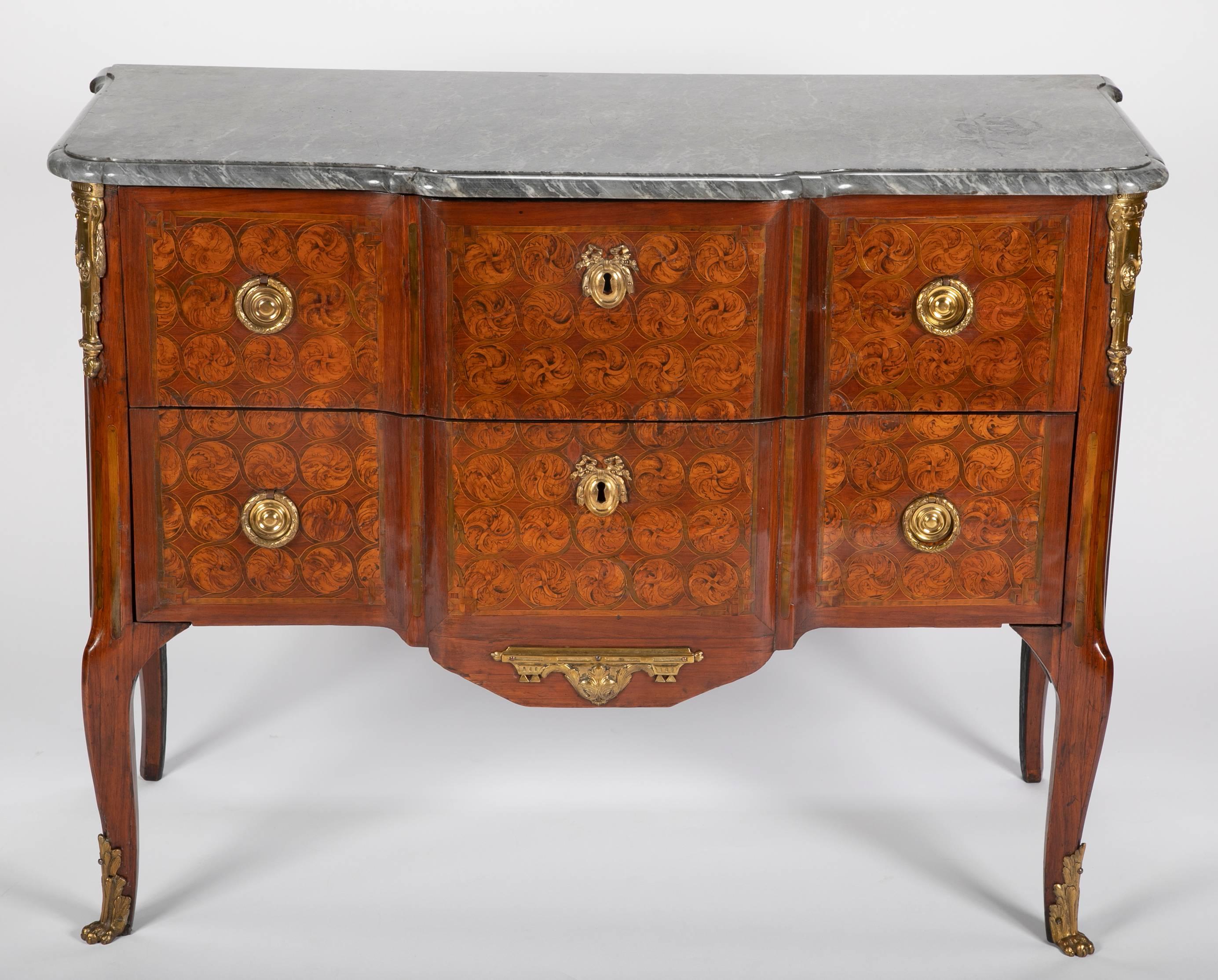 A French Transitional period commode of exceptional quality in tulipwood and amaranth inlaid with concentric circles and surmounted with a gray marble top, circa 1760. Ex. Collection: St Louis Art Museum. Measures: 34.5 H x 42.5 W x 21 D.