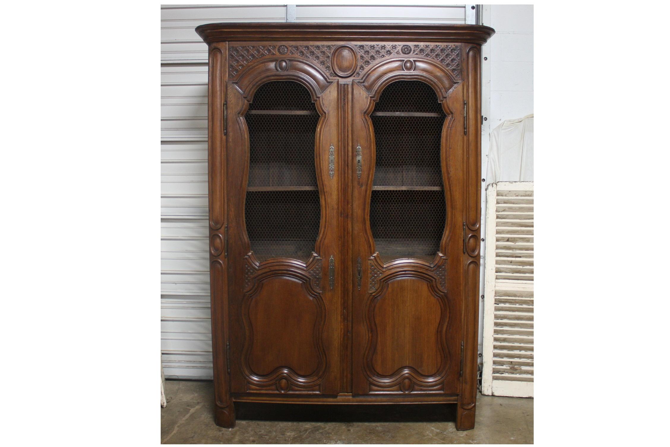 This wonderful rustic vitrine or bookcase has beautiful carvings with chicken wire on the doors. The dimensions of the body are 60.25''W x 18.5''D.
The inside depth is 14.5''D.