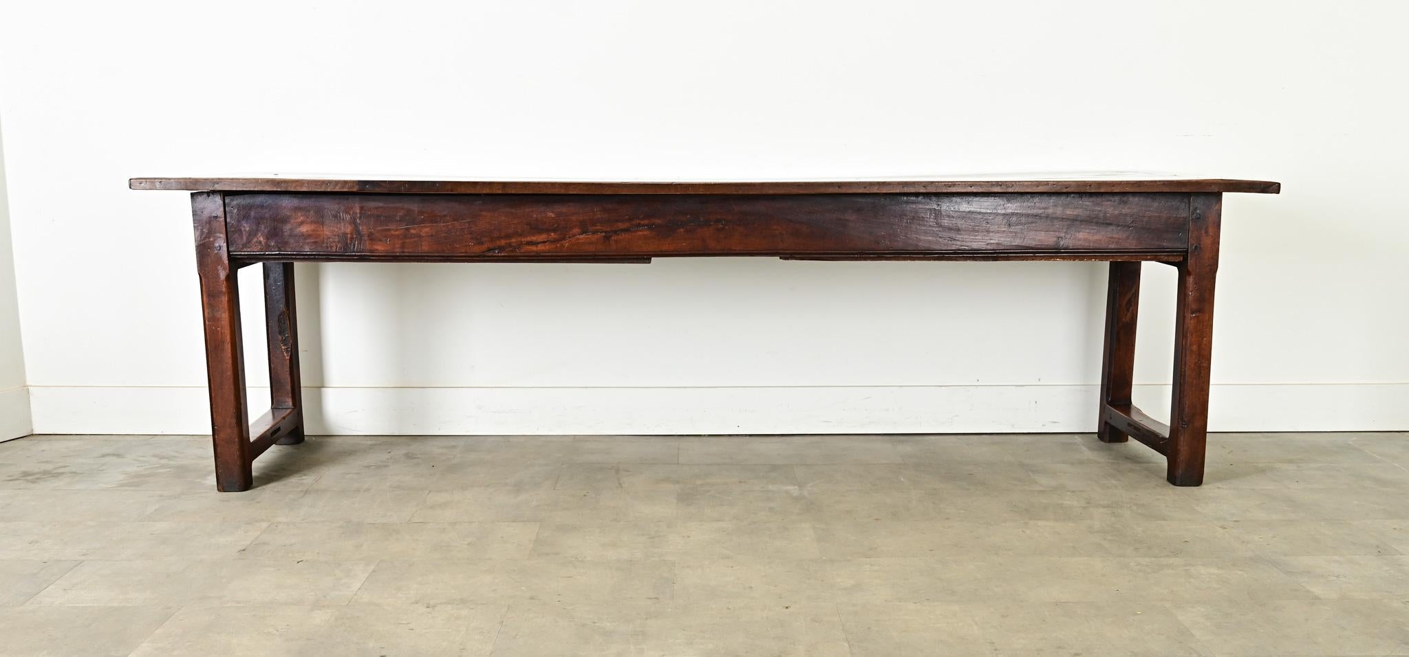 Une étonnante table de ferme en noyer français du XVIIIe siècle aux proportions robustes et aux deux tiroirs tout aussi étonnants. Le plateau en planches simples, disposé en planche à pain, présente plusieurs couches de patine sur le grain de
