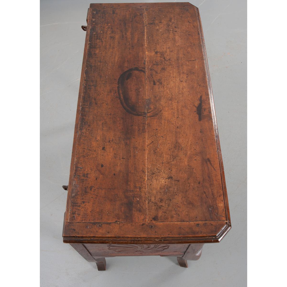 A small walnut petrin or dough bin with a deep, rich patina. This wonderful antique is hand-pegged with treenails. The top is a lid that when lifted opens a single storage compartment for proofing bread. A wonderfully carved shell and wheat motif