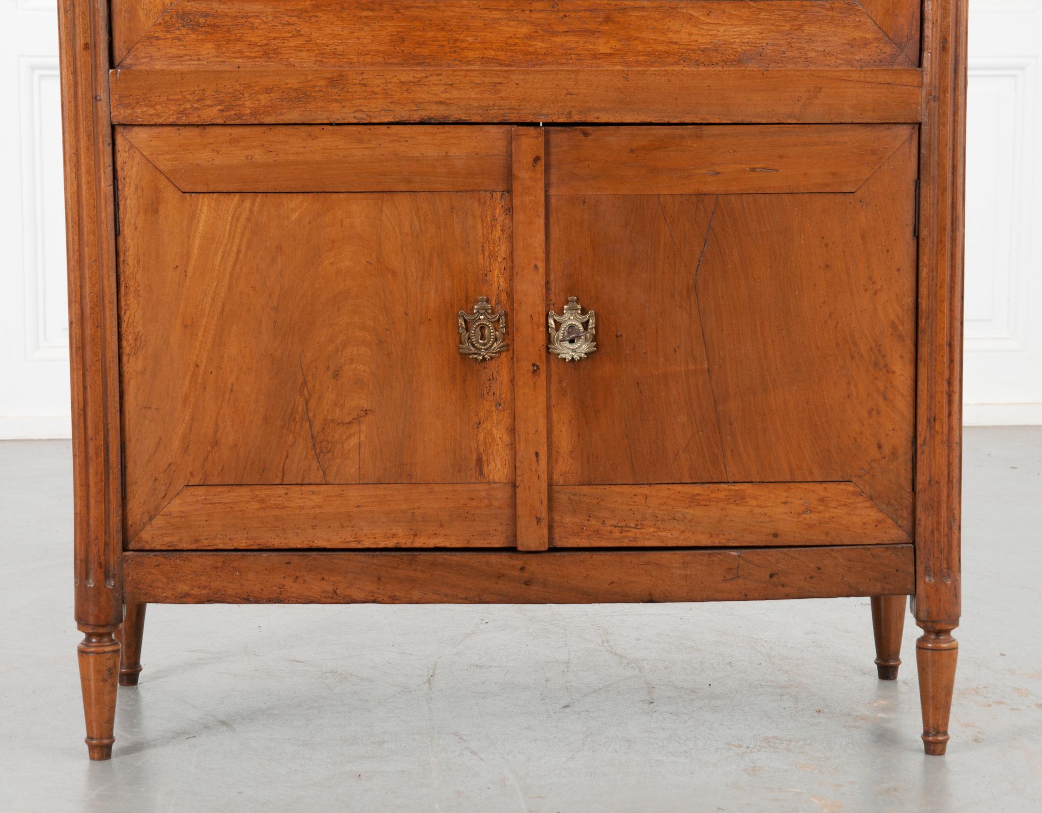 This wonderful solid walnut secre´taire a` abattant was constructed in the period of Louis XVI, circa 1780. A single, slim drawer at the top features brass drop ring pulls and a decorative escutcheon that matches throughout the piece. The front of