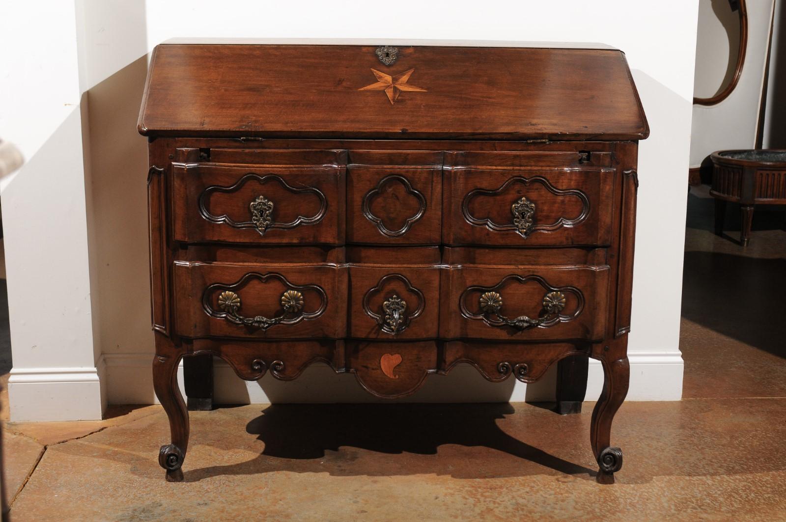 A French Louis XV period walnut slant-front desk on commode from the 18th century, with star inlay, crossbow front and quadrilobe motifs. Born in France during the 18th century, this exquisite walnut desk features a slant-front bureau, adorned in