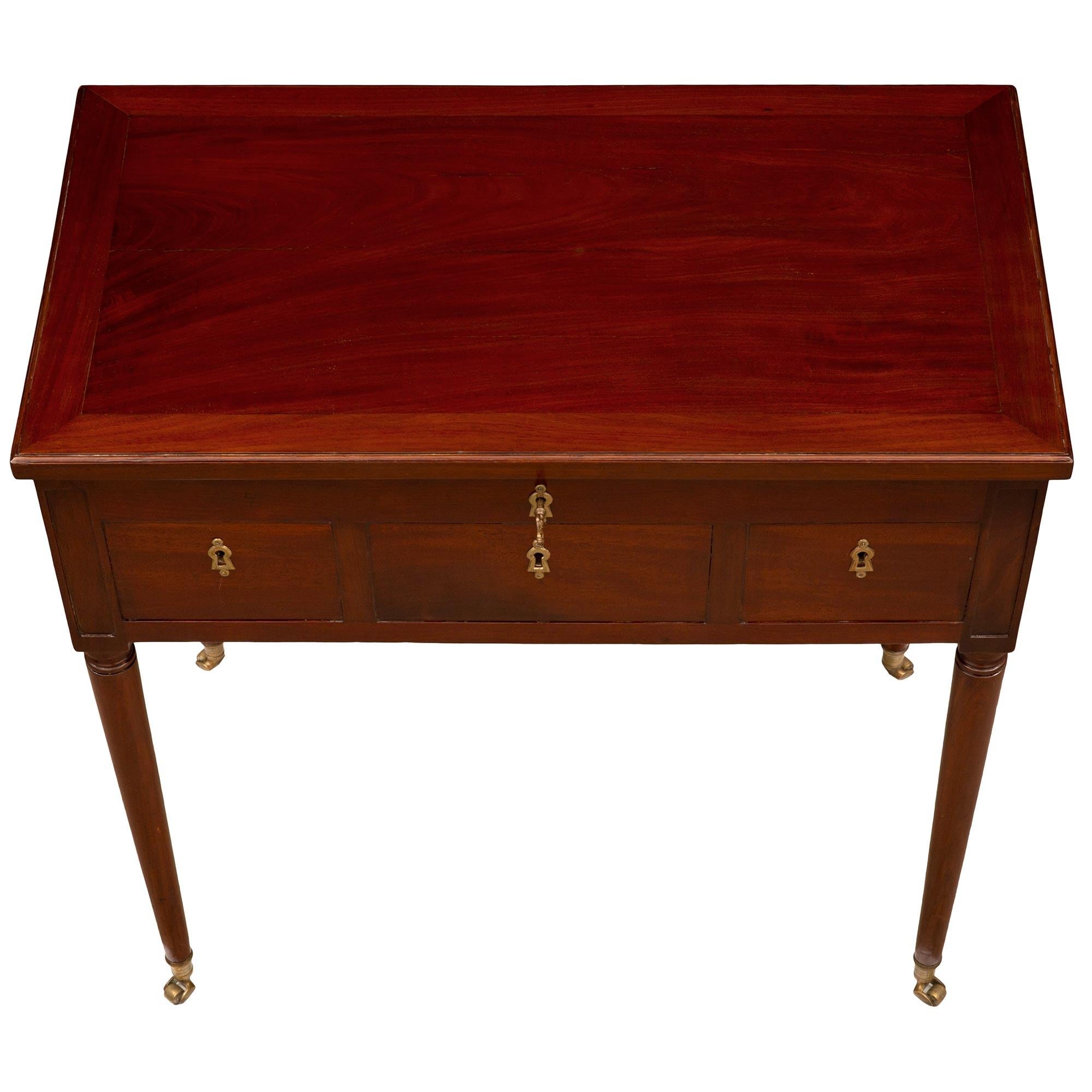 A unique and most elegant French 18th Louis XVI period Mahogany vanity table. The table is raised by slender circular tapered legs retaining their fine original ormolu casters. The straight apron displays three faux drawers each decorated with