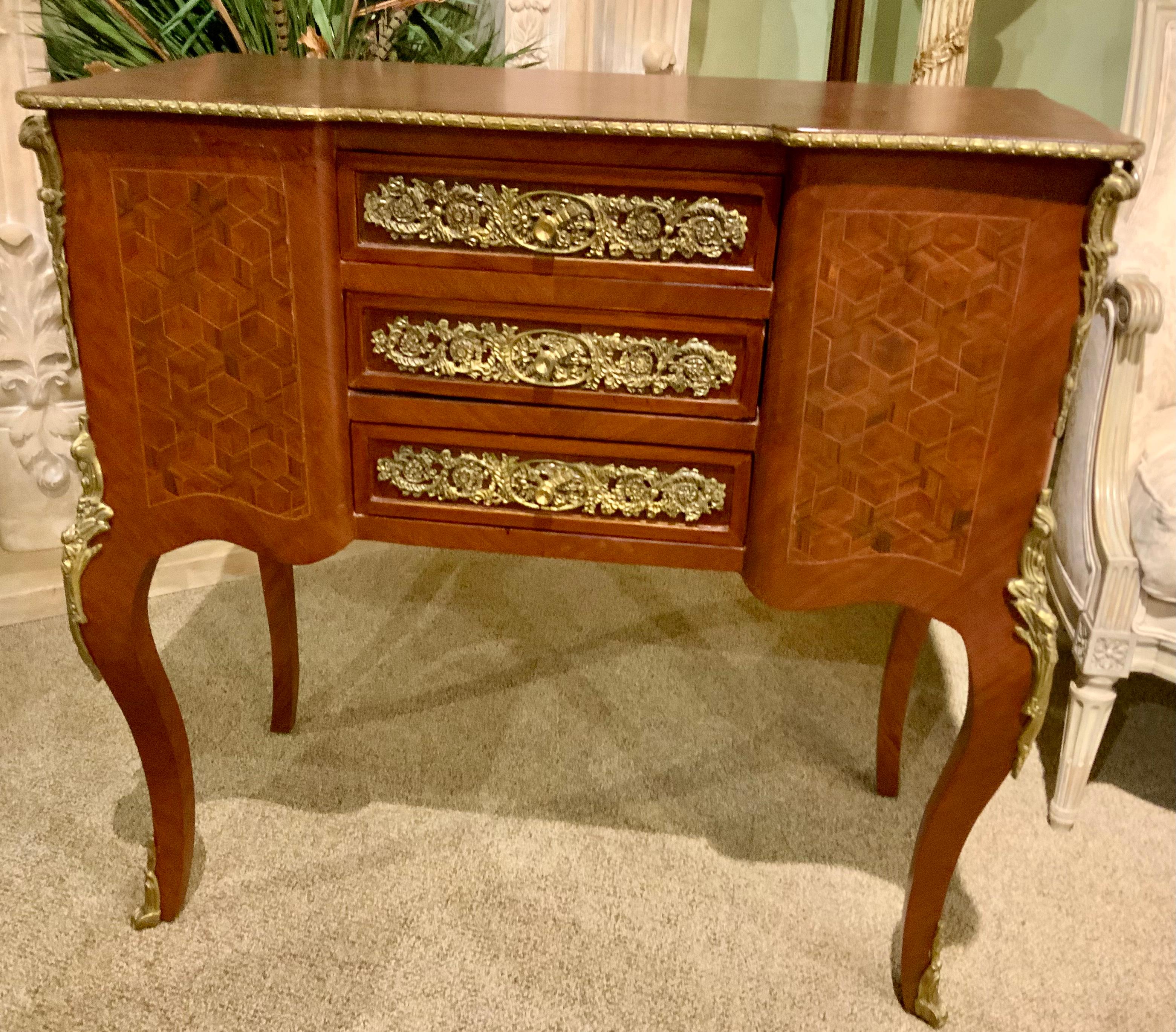This cabinet could have a multitude of uses. It is a good size to use
Bedside or between two chairs. It has three drawers in the center
Of the piece that draw easily. Scrolling bronze dore ormolu decorates
The front of the drawers with a knob