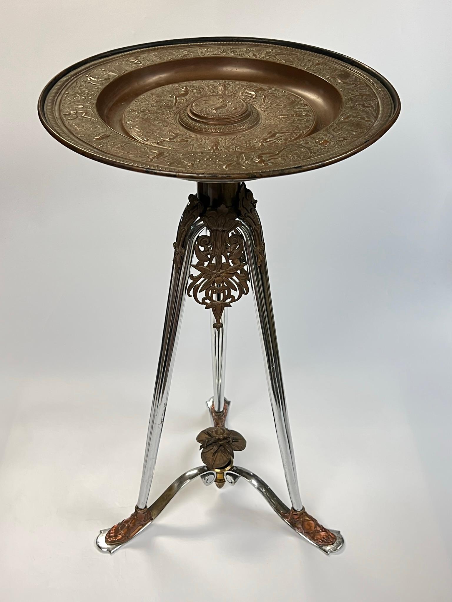 Antique stand in the Roman neoclassical style with round bronze charger decorated with Bacchanal theme depicting maidens and soldiers, with chromium plated legs terminating in feet wearing leather sandals. After a model by Francois Briot (ca