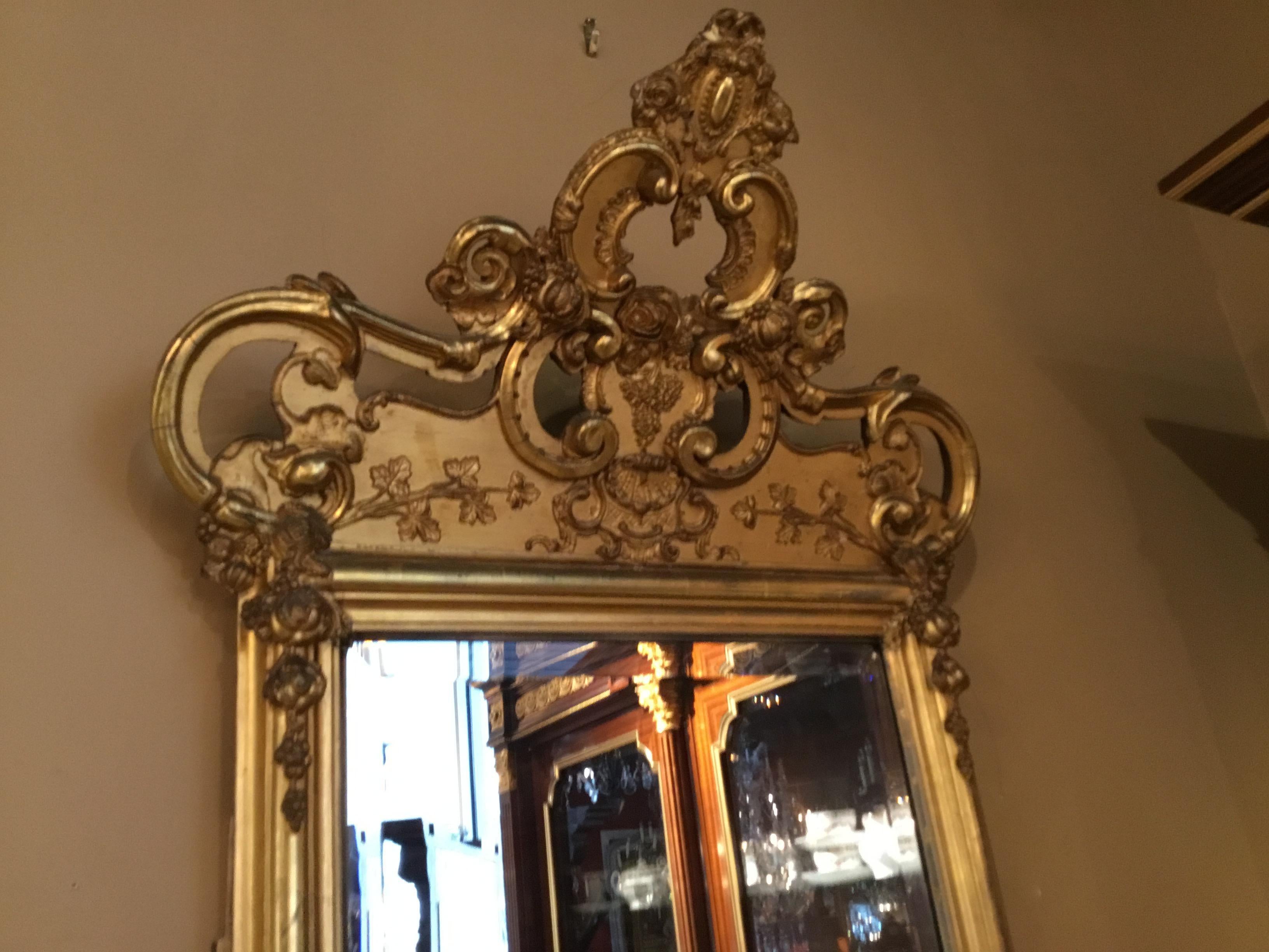 Lovely old original giltwood with antique patina. The top crest bends gently forward in design.
Fruit and foliate carvings decorate this exceptional mirror.