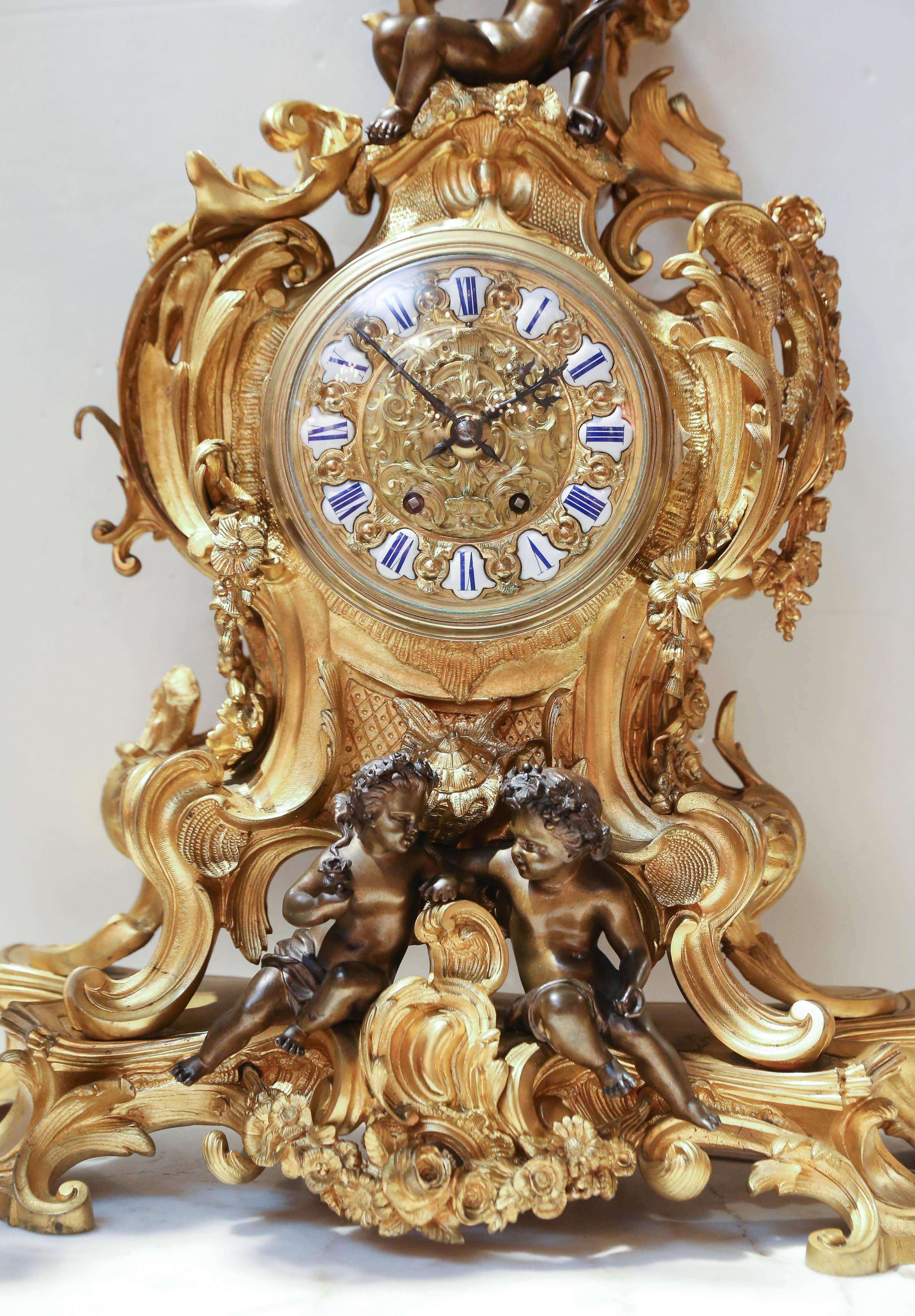 Magnifico tre pezzi in bronzo dorato francese della metà del secolo scorso
Set da guarnizione in ormolu. Il set è composto da un orologio e da due 
Candelabro a sei luci in stile Luigi XV con motivi floreali e
Festoni d'uva che si intrecciano con