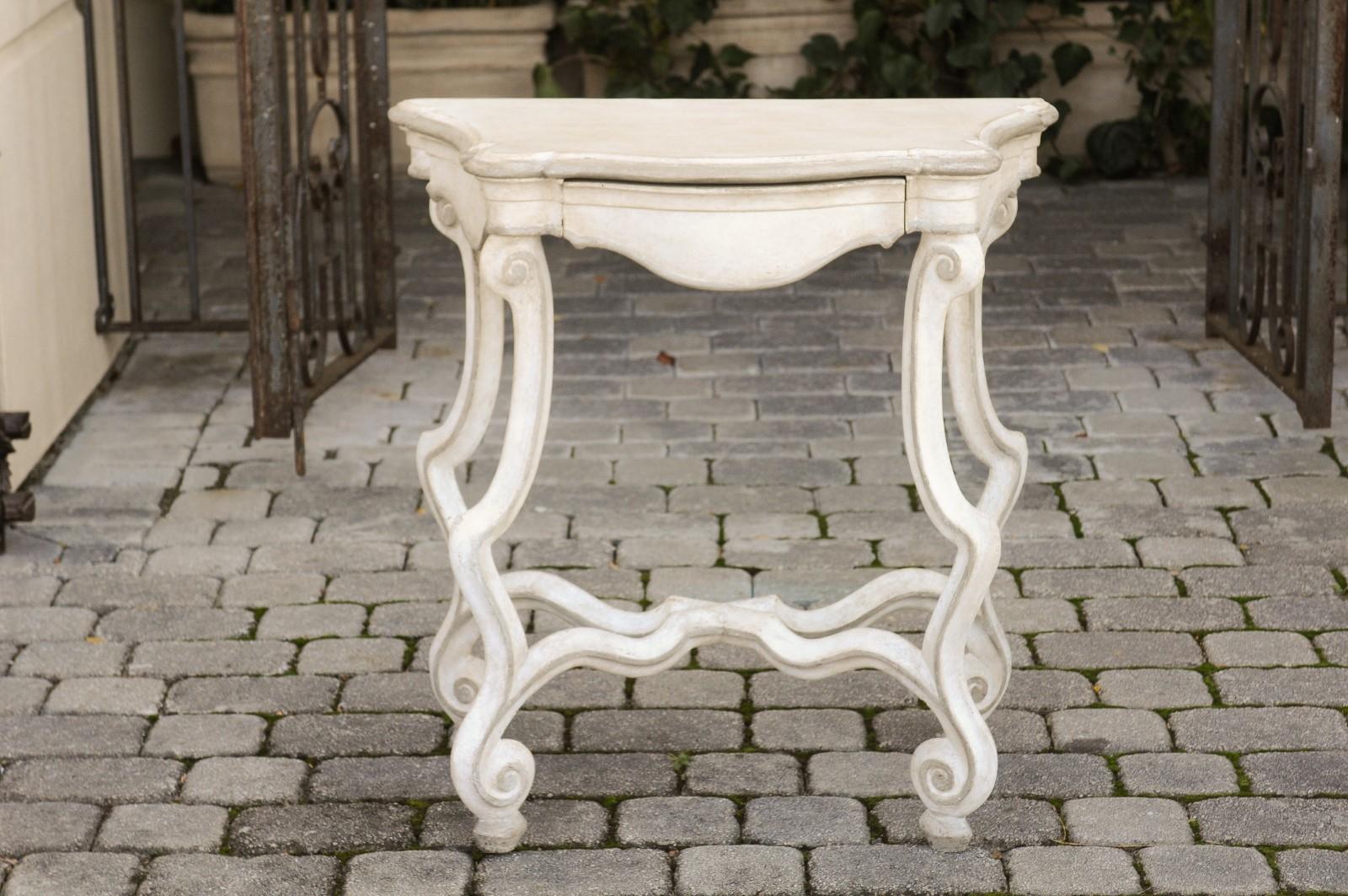 A French Rococo style painted console table from the early 20th century, with frieze drawer, scrolling legs and cross stretcher. Born in France at the turn of the 20th century during the Belle-Époque era, this exquisite painted console table