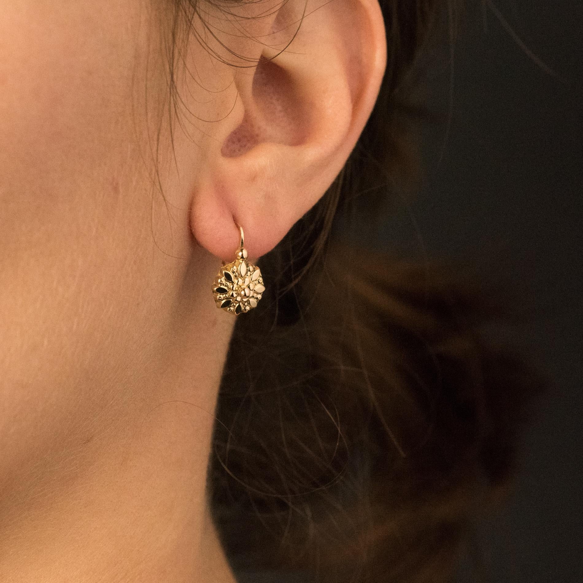 For pierced ears.
Earrings in 18 karats yellow gold.
Lovely gold sleepers earrings, they are engraved with a floral decoration and set with a gold pearl on the top. The clasp sneaks from the back.
Height: 1.5 cm, width: 9 mm, thickness: 4 mm.
Total