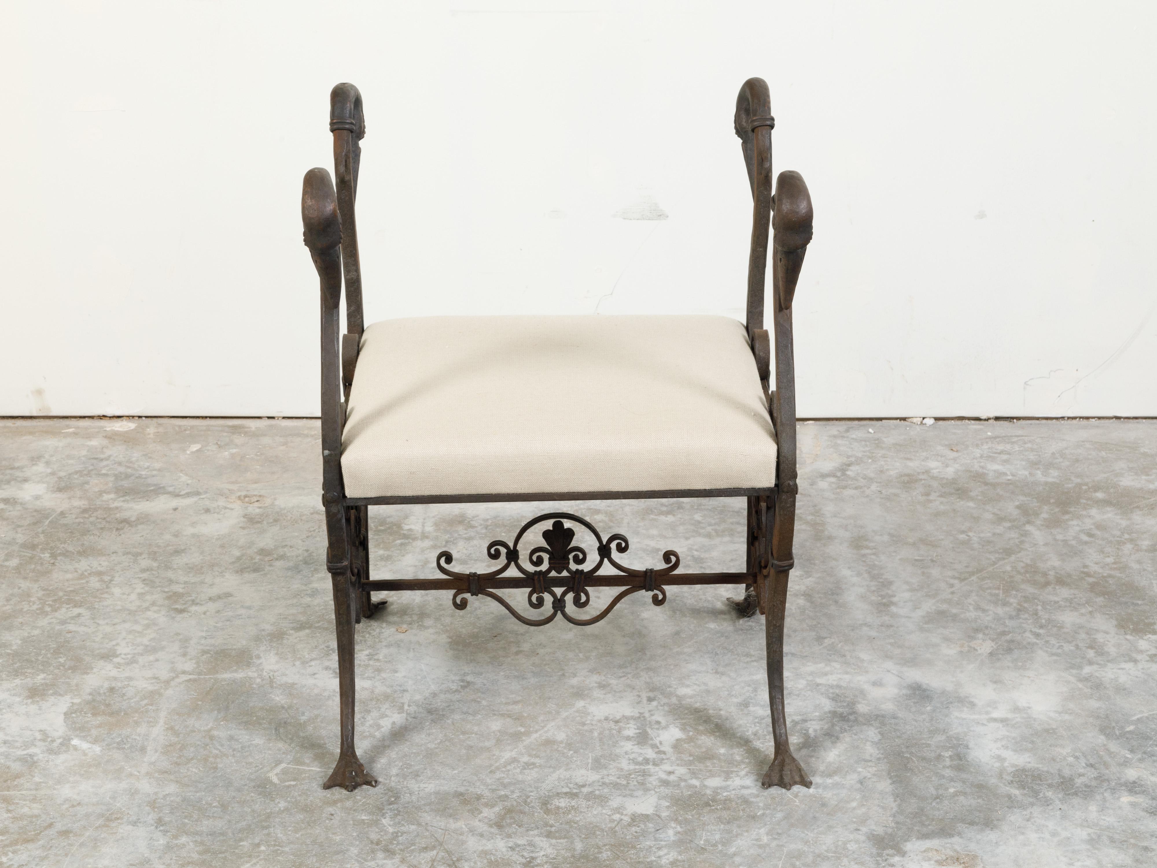 A French Belle Époque iron and bronze stool from the early 20th century, with swan heads, palmed feet and upholstery. Created in France during the Belle Époque era, this iron and bronze stool features a rectangular seat with neutral toned